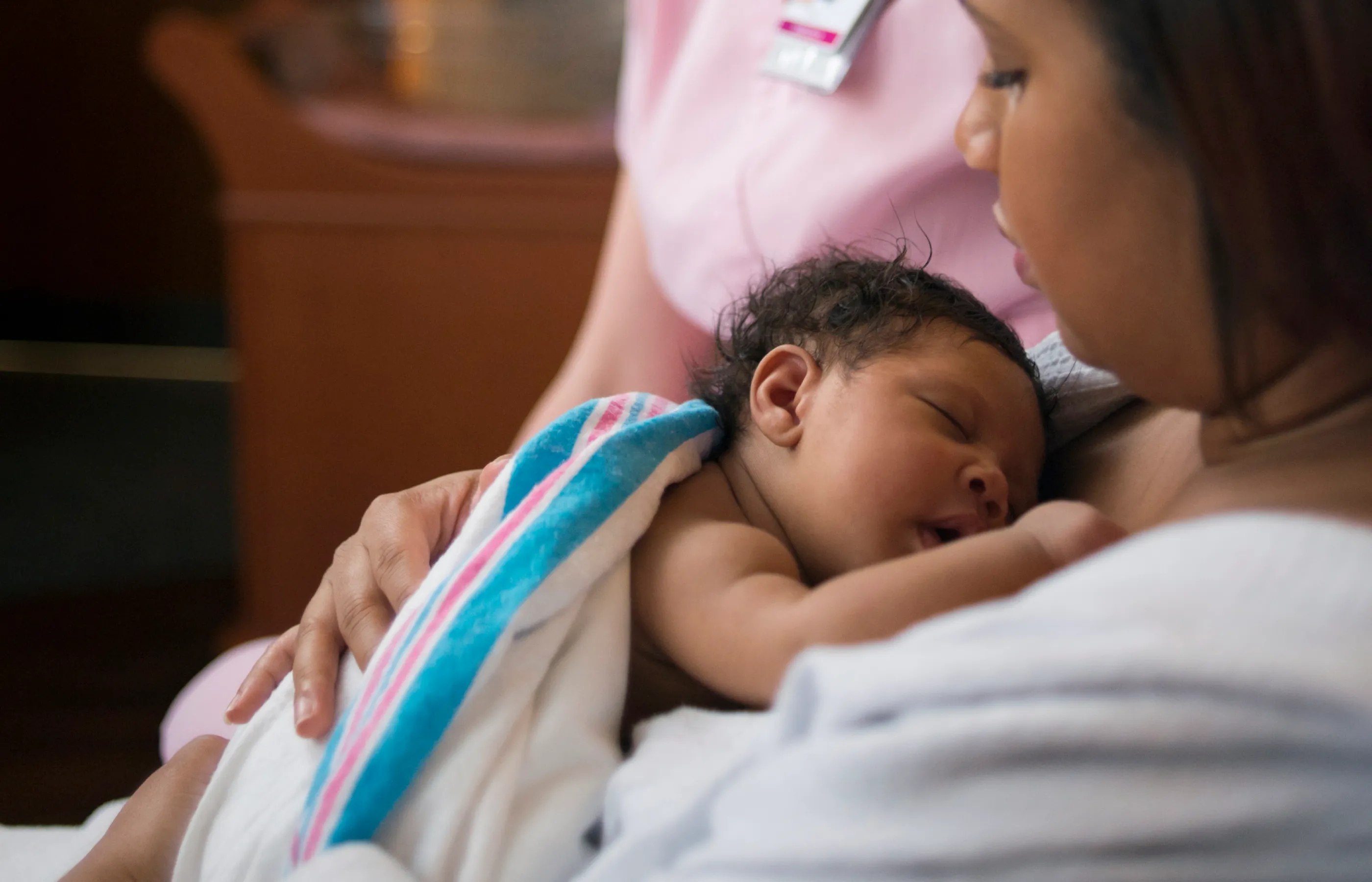 Lactation consultant teaching new mother how to breastfeed newborn baby