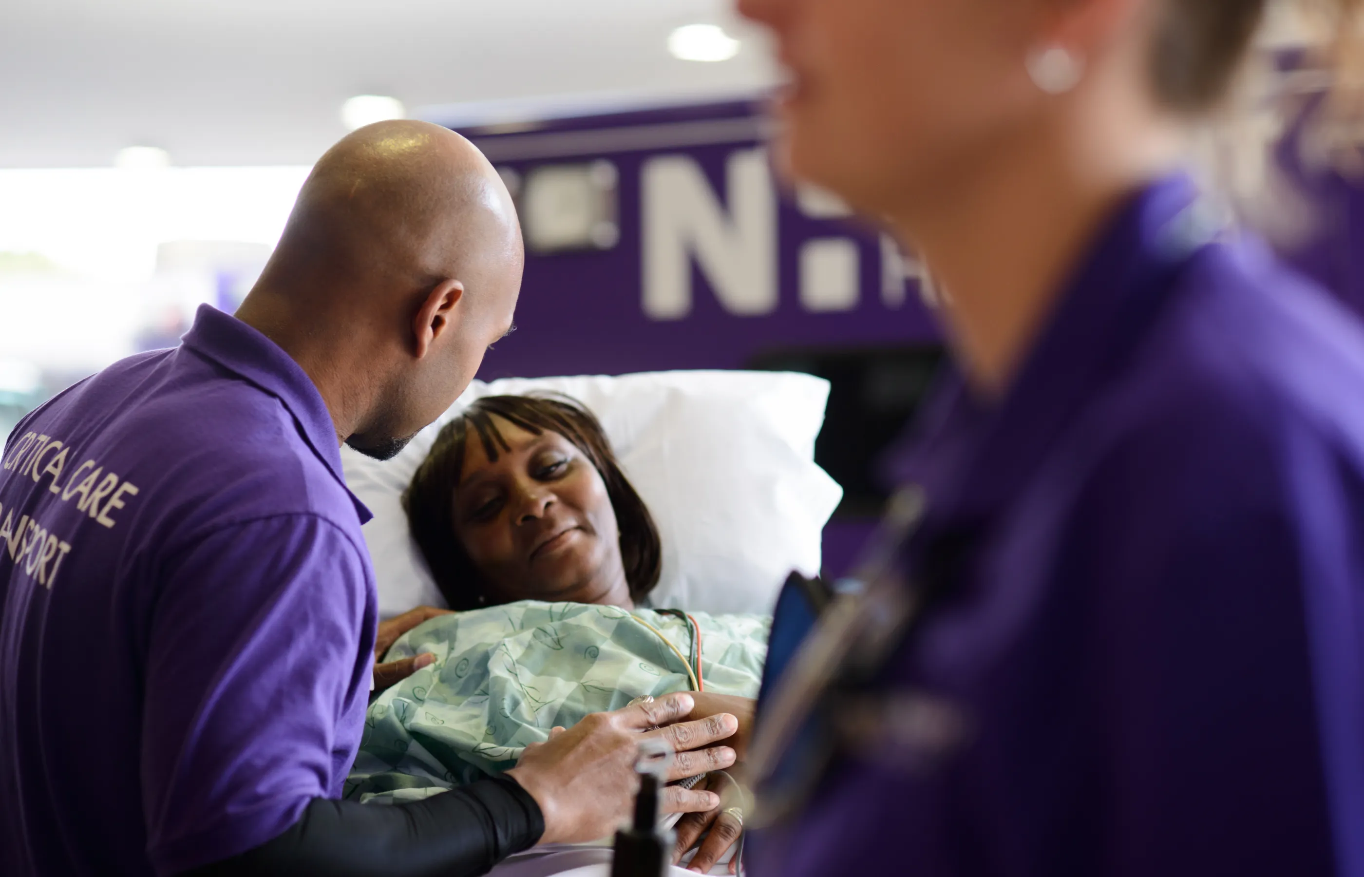 A Novant Health team member is assisting a woman as she is laying on a stretcher. 