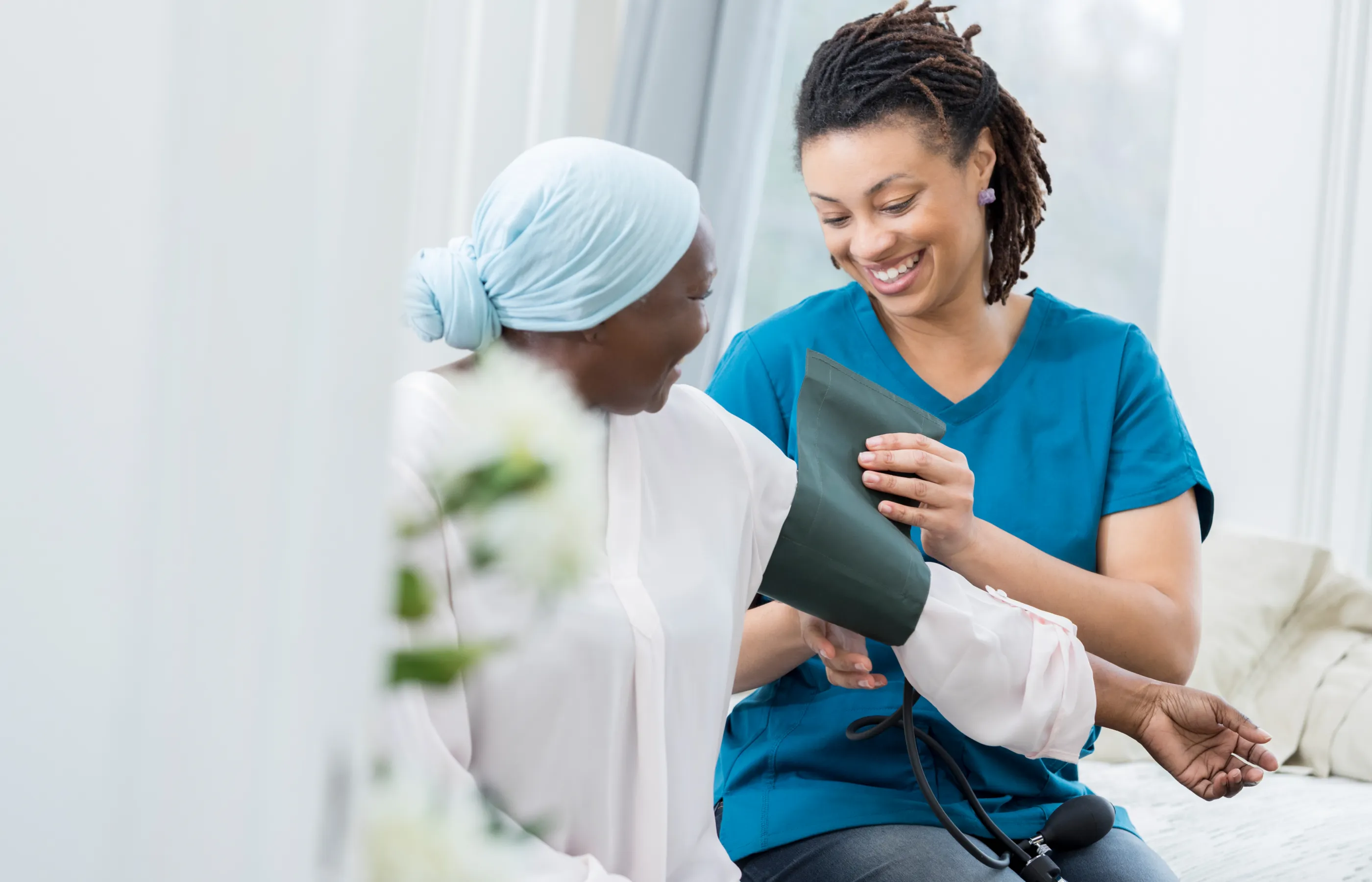 A nurse is placing a blood pressure cuff on a cancer patient. 