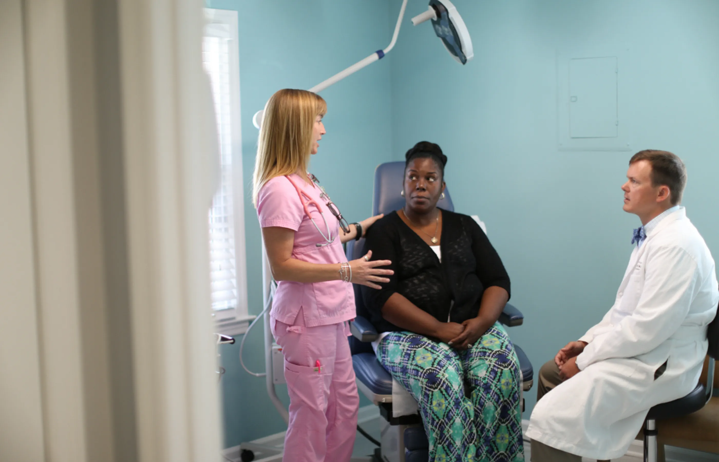 A Novant Health patient, doctor, and nurse are all together in exam room talking.  A Novant Health patient, doctor, and nurse are all together in exam room talking.