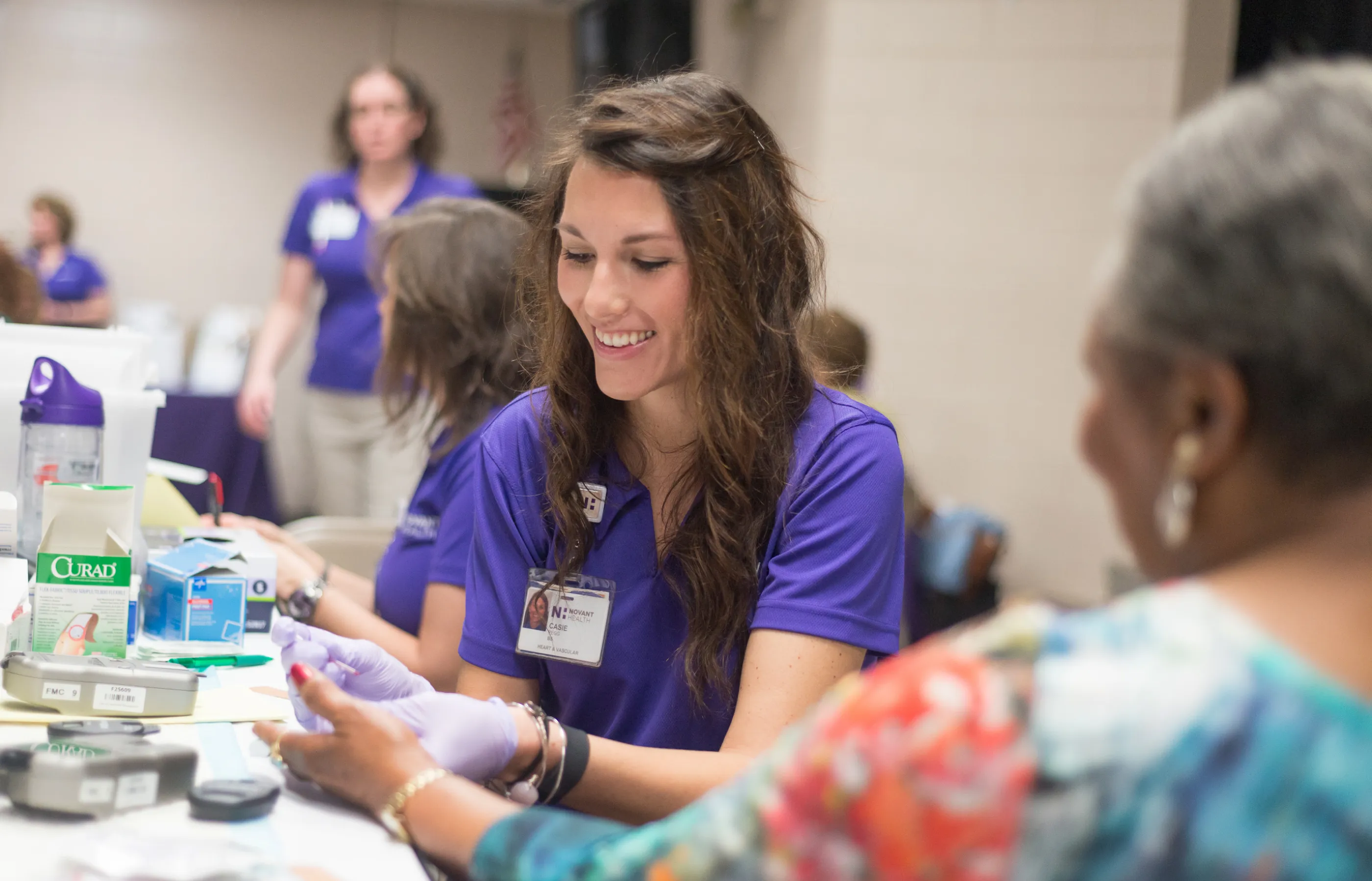 At a community screening event, a Novant Health team member is checking a patients blood glucose level. 