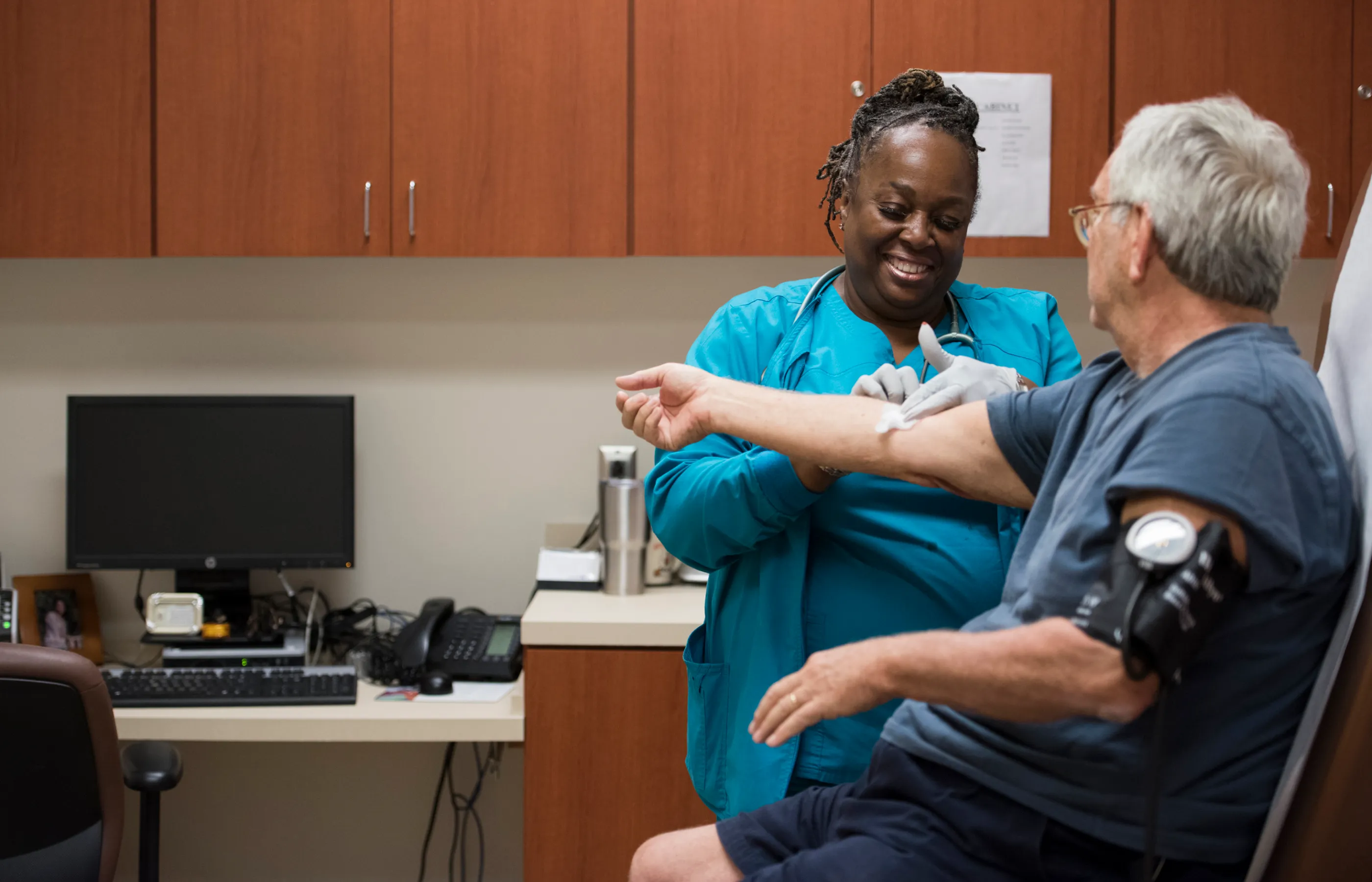 A Novant Health lab specialist and patient are in clinic lab taking blood pressure and completing lab testing. 