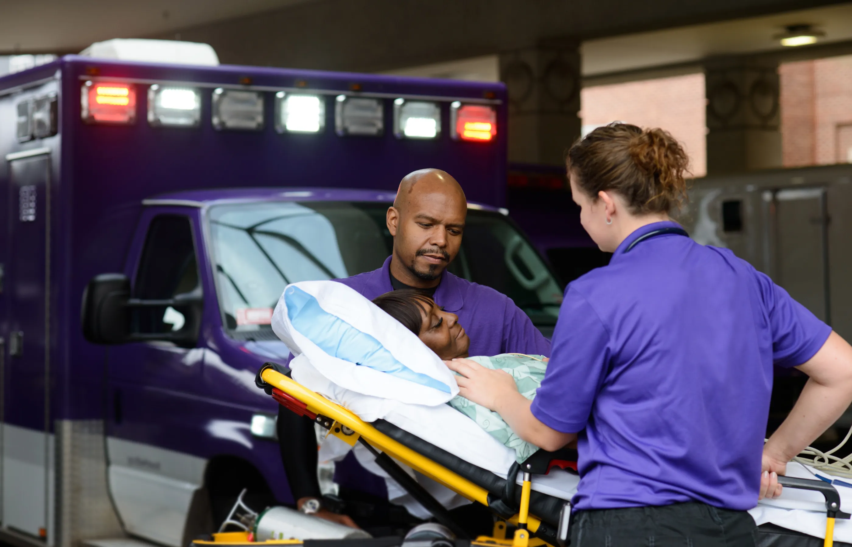 Two Novant Health team members are wheeling a patient on a stretcher. 