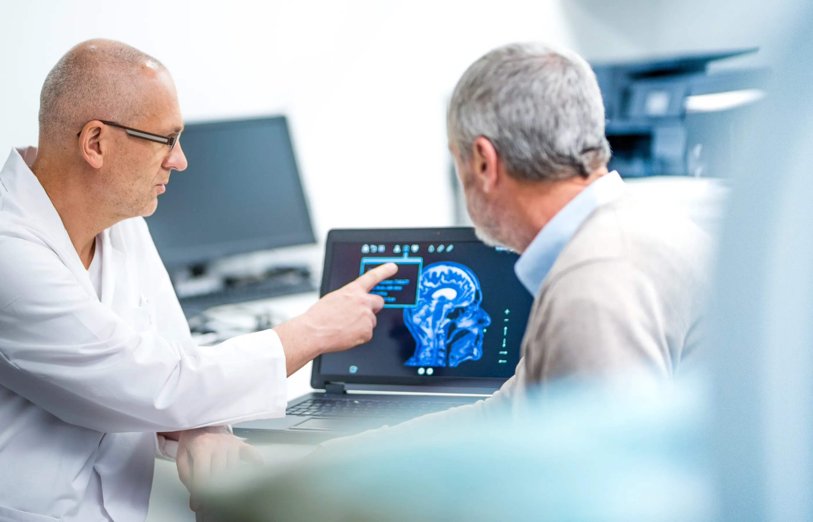 A health care provider is reviewing a brain scan with a patient.  A health care provider is reviewing a brain scan with a patient.