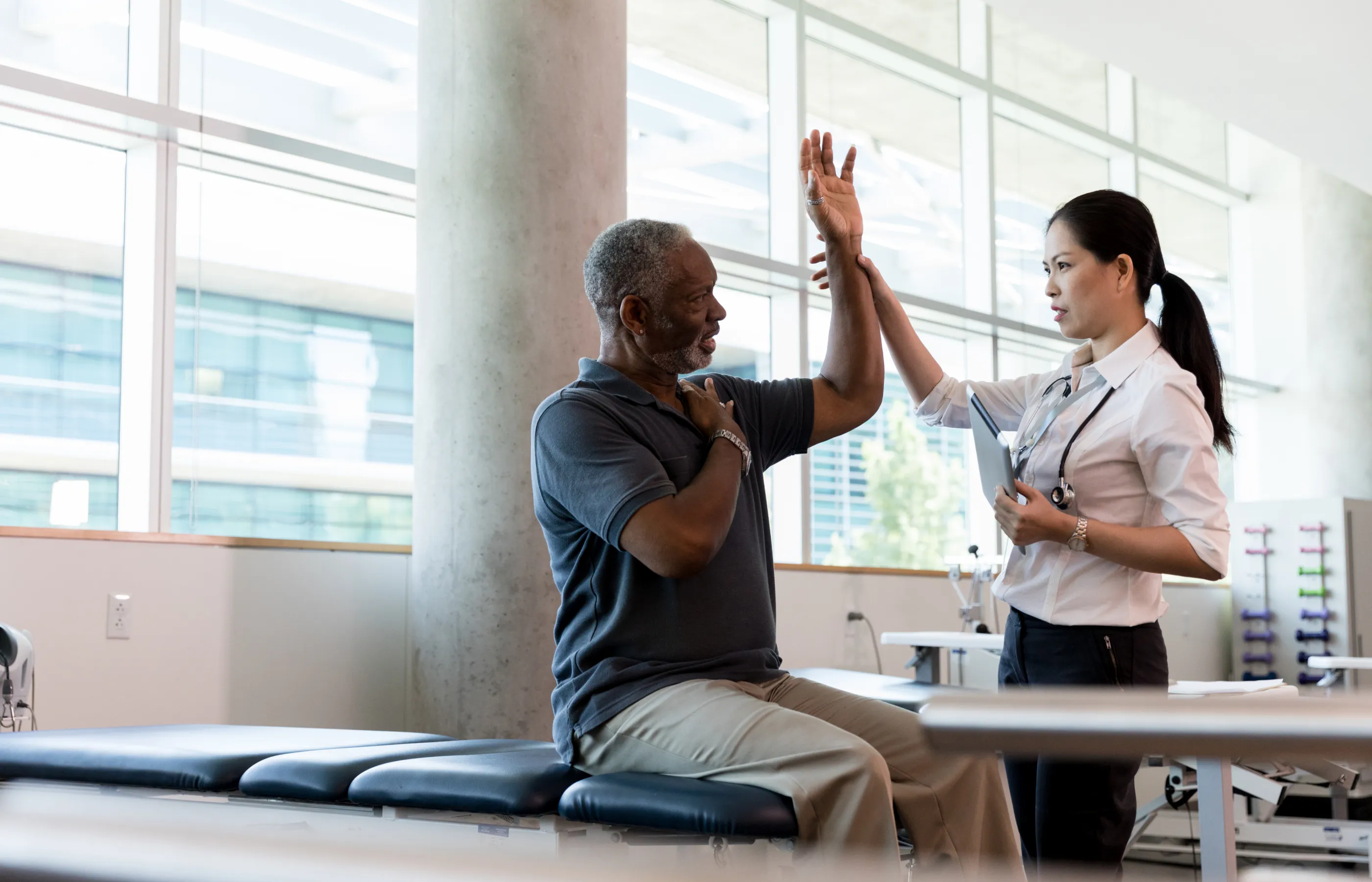 A physical therapist is assisting a patient as they lift their arm.  