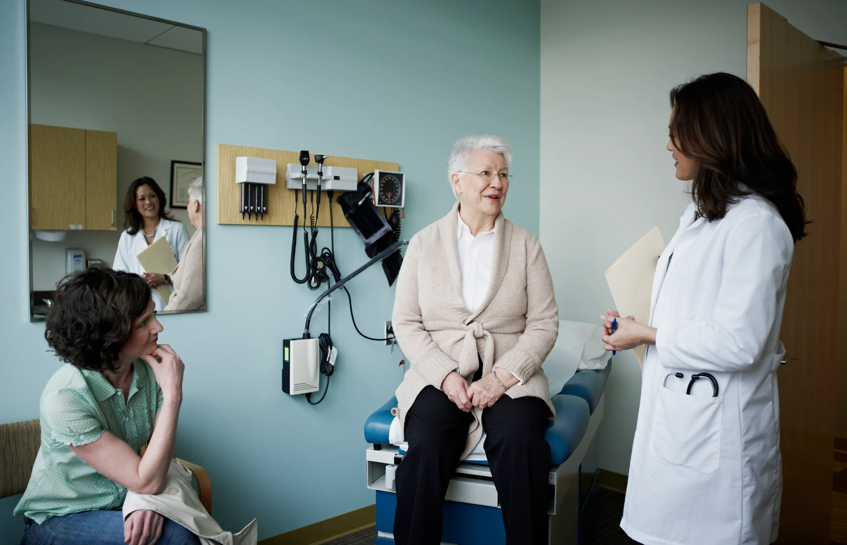 A female physician speaks with a senior woman patient in the exam room