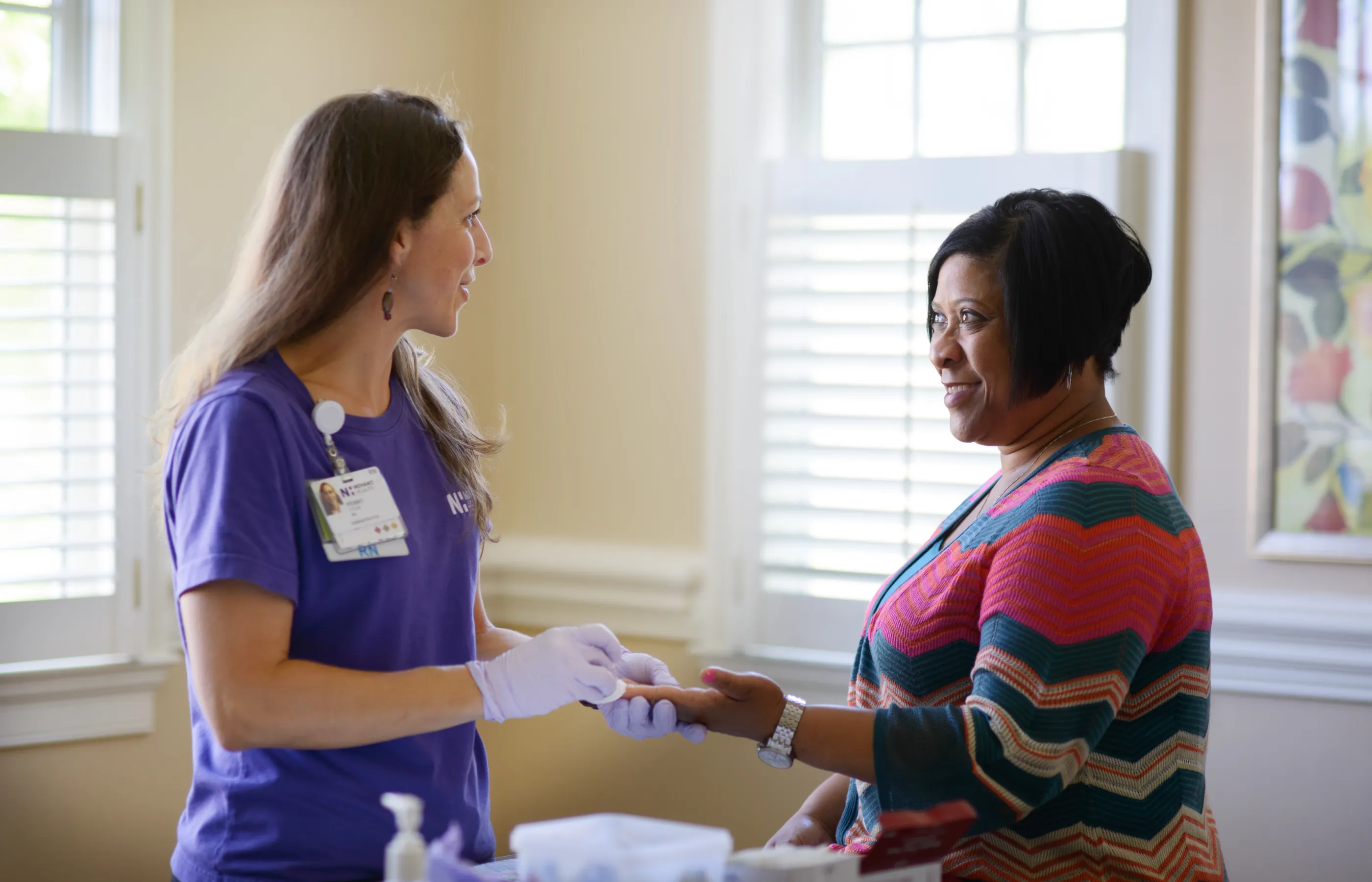 Novant Health registered nurse is preparing a patients for a finger prick screening. 