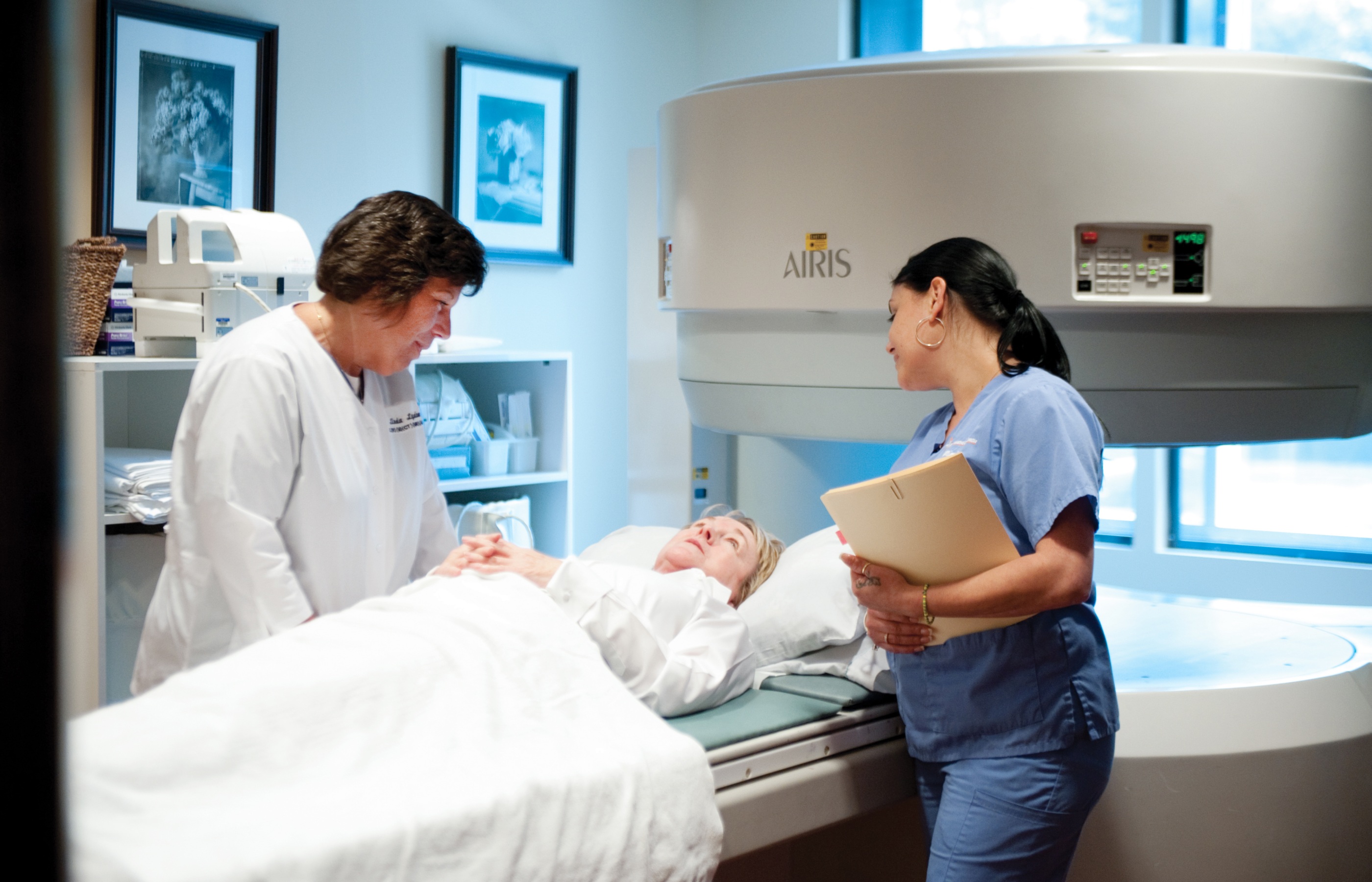 Two team members are talking with a patient as they prepare for an imaging scan.