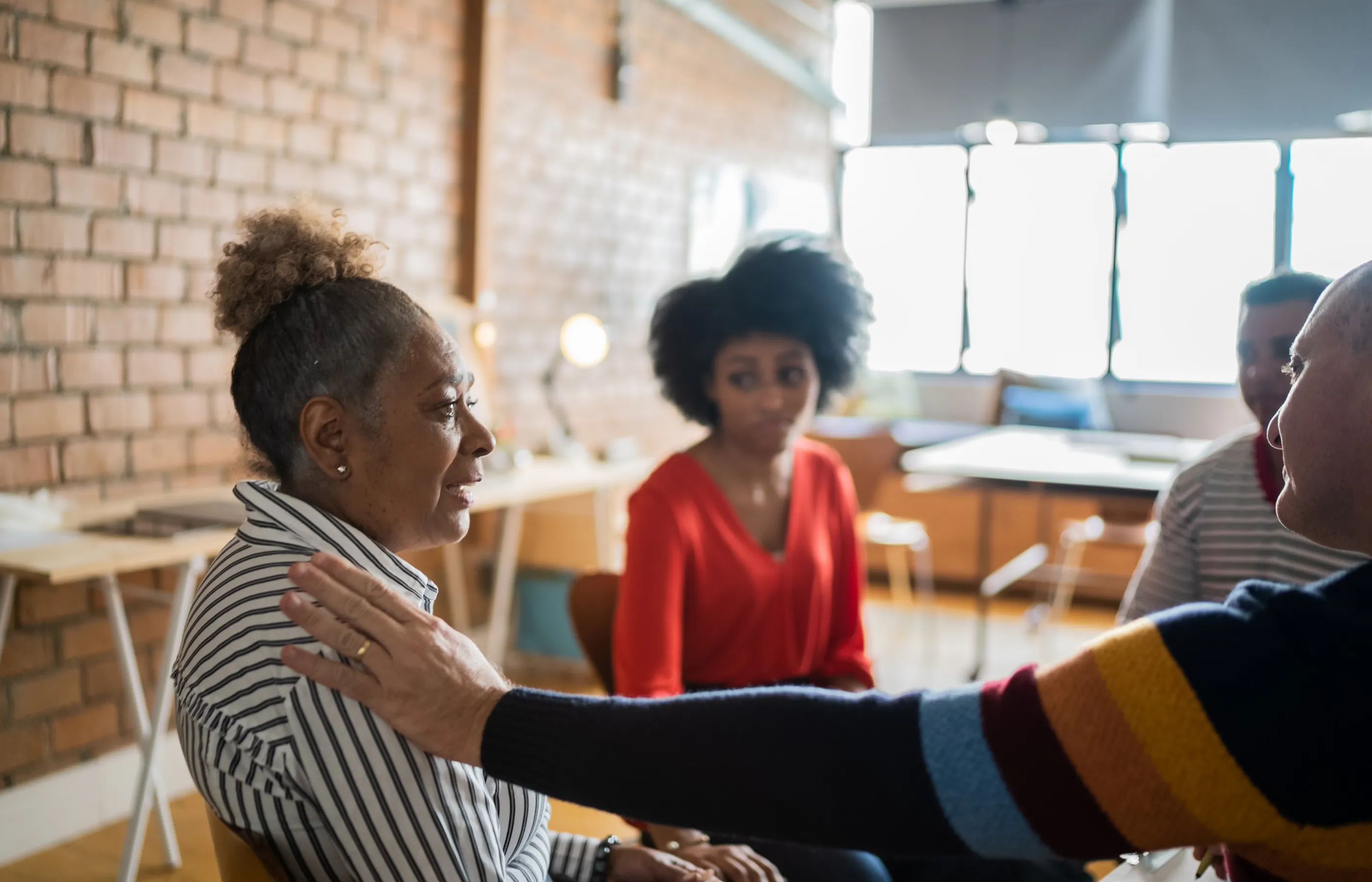 A group of people are talking and supporting one another in a support group session.  A group of people are talking and supporting one another in a support group session.