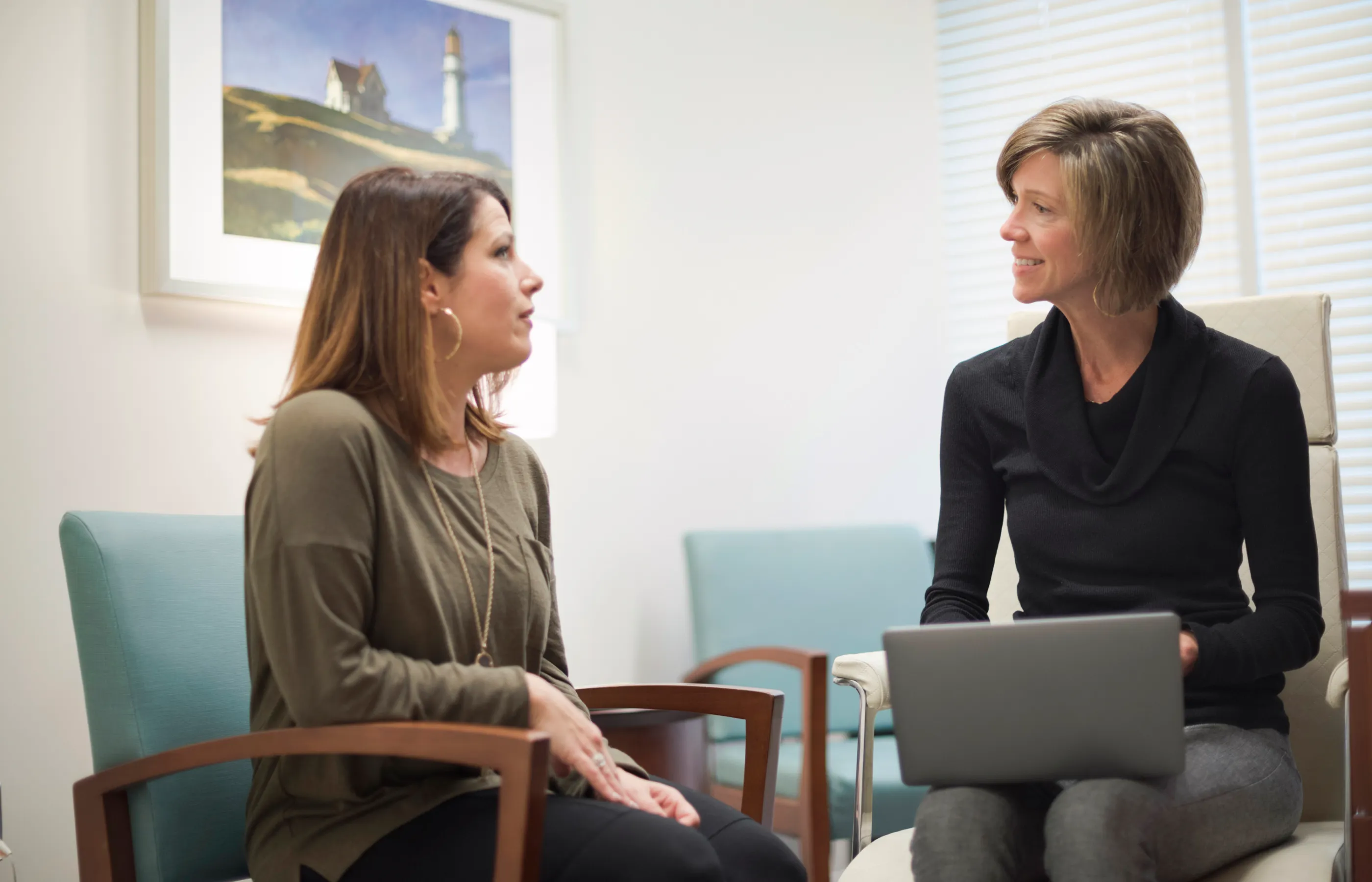 A health care provider is typing on a computer as she talks to a patient. 