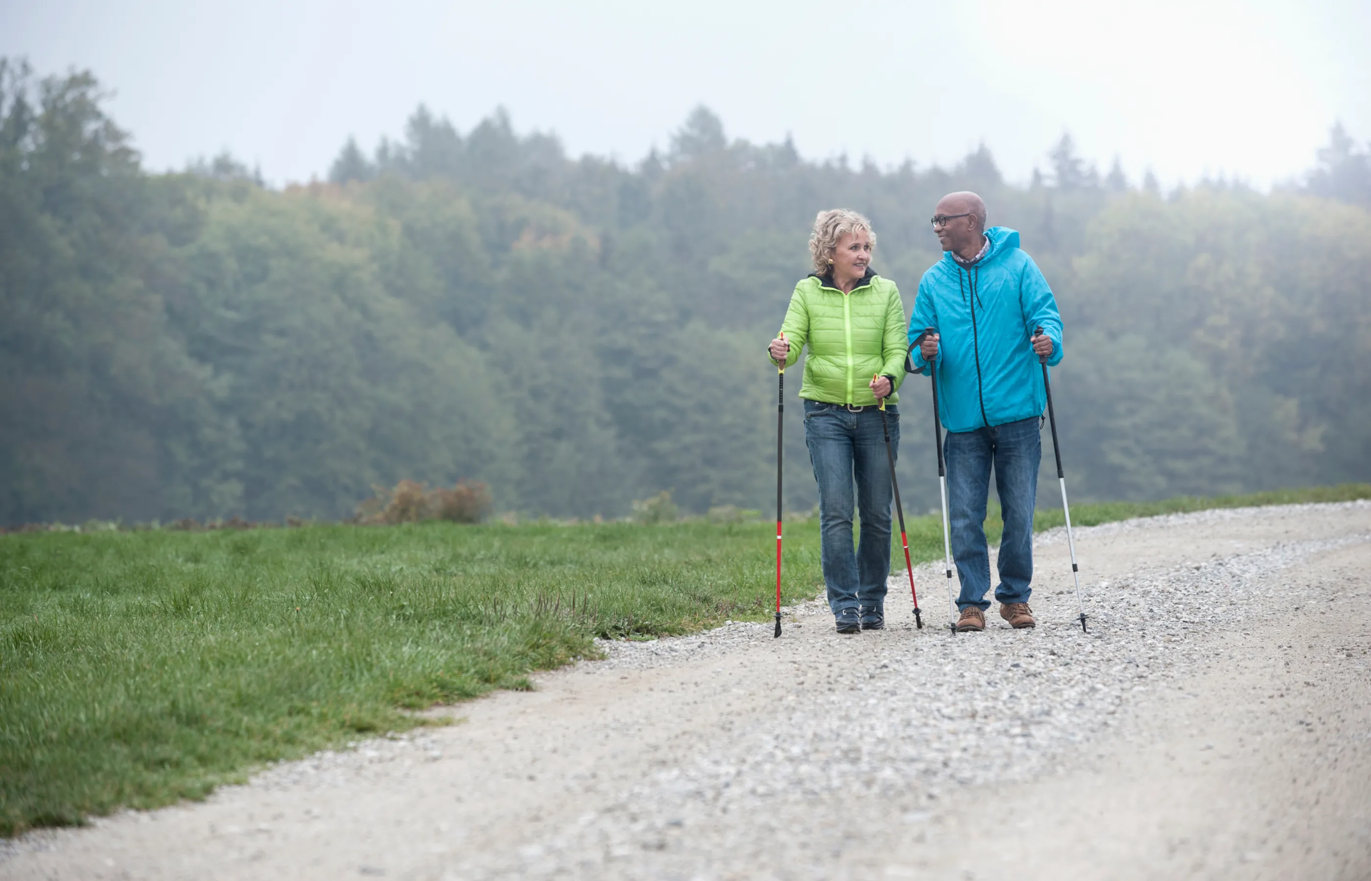 A senior couple is out hiking a trail together. 