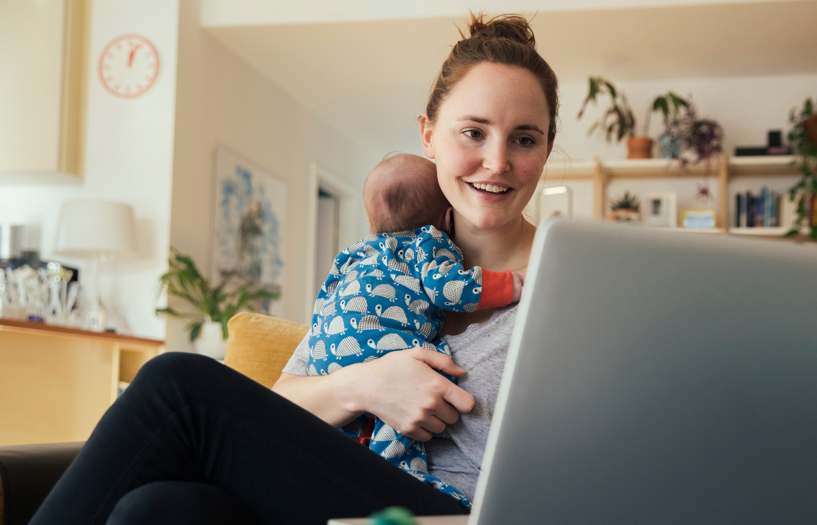 Woman holding a child while using a laptop Woman holding a child while using a laptop