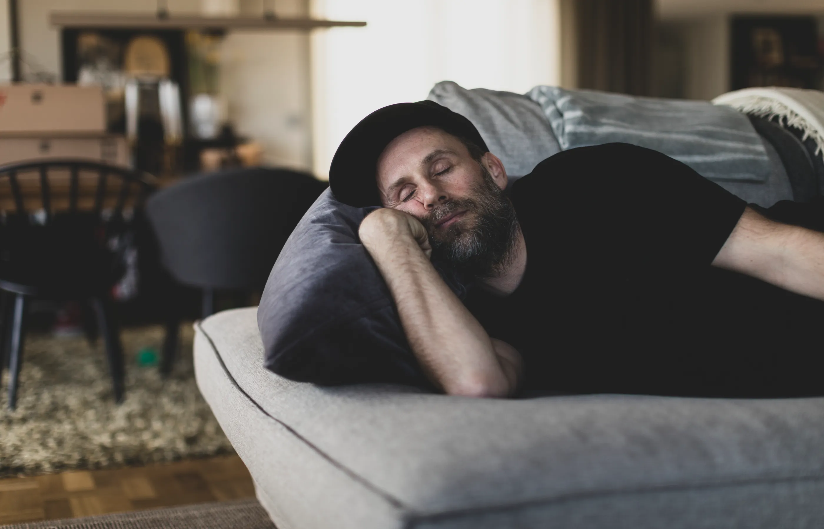Adult male with a beard sleeping on his couch at home. 