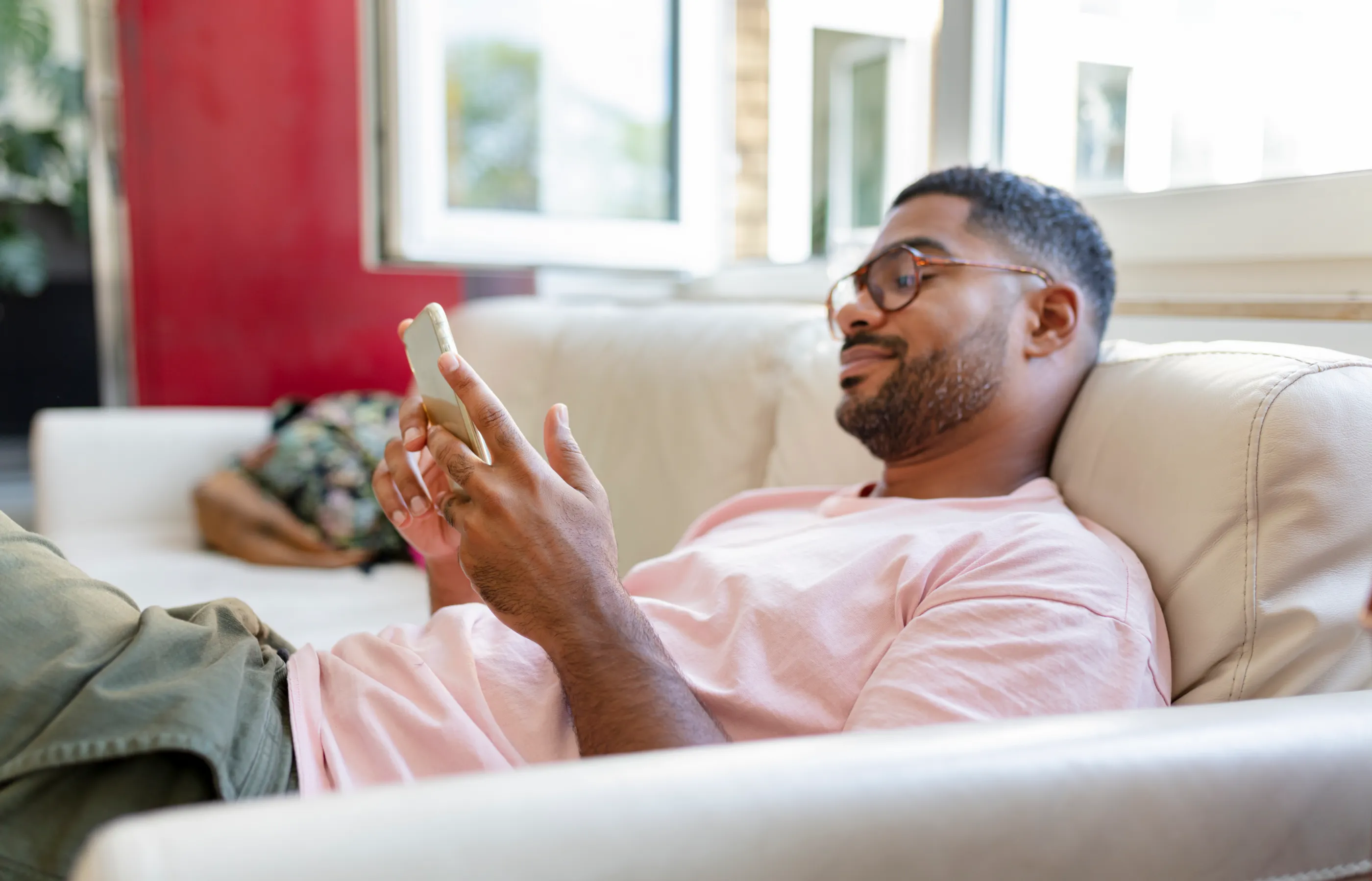 A man is lying on his couch reviewing information on his smart phone. A man is lying on his couch reviewing information on his smart phone.