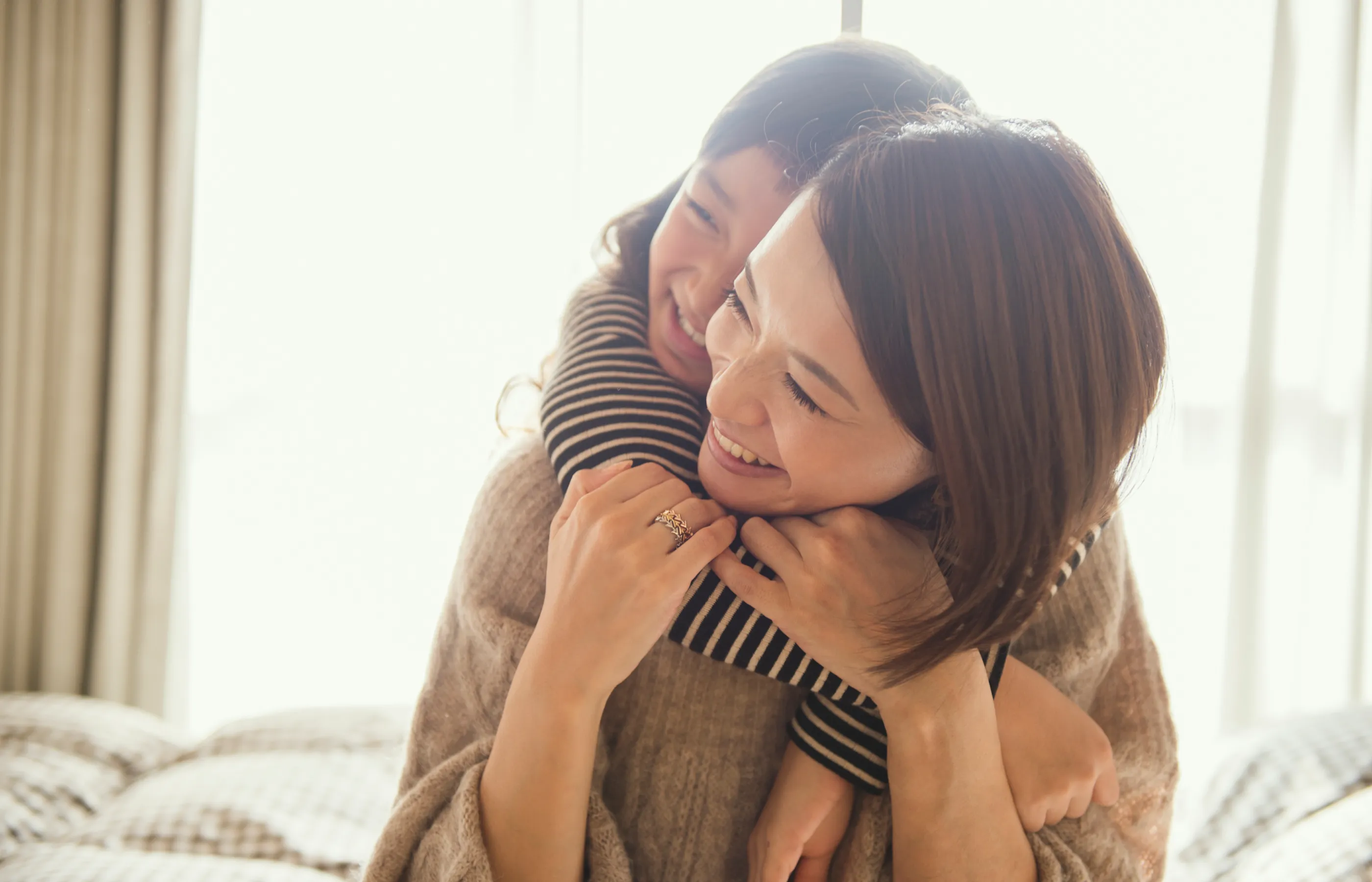 Mother and daughter smiling and hugging in a bedroom
