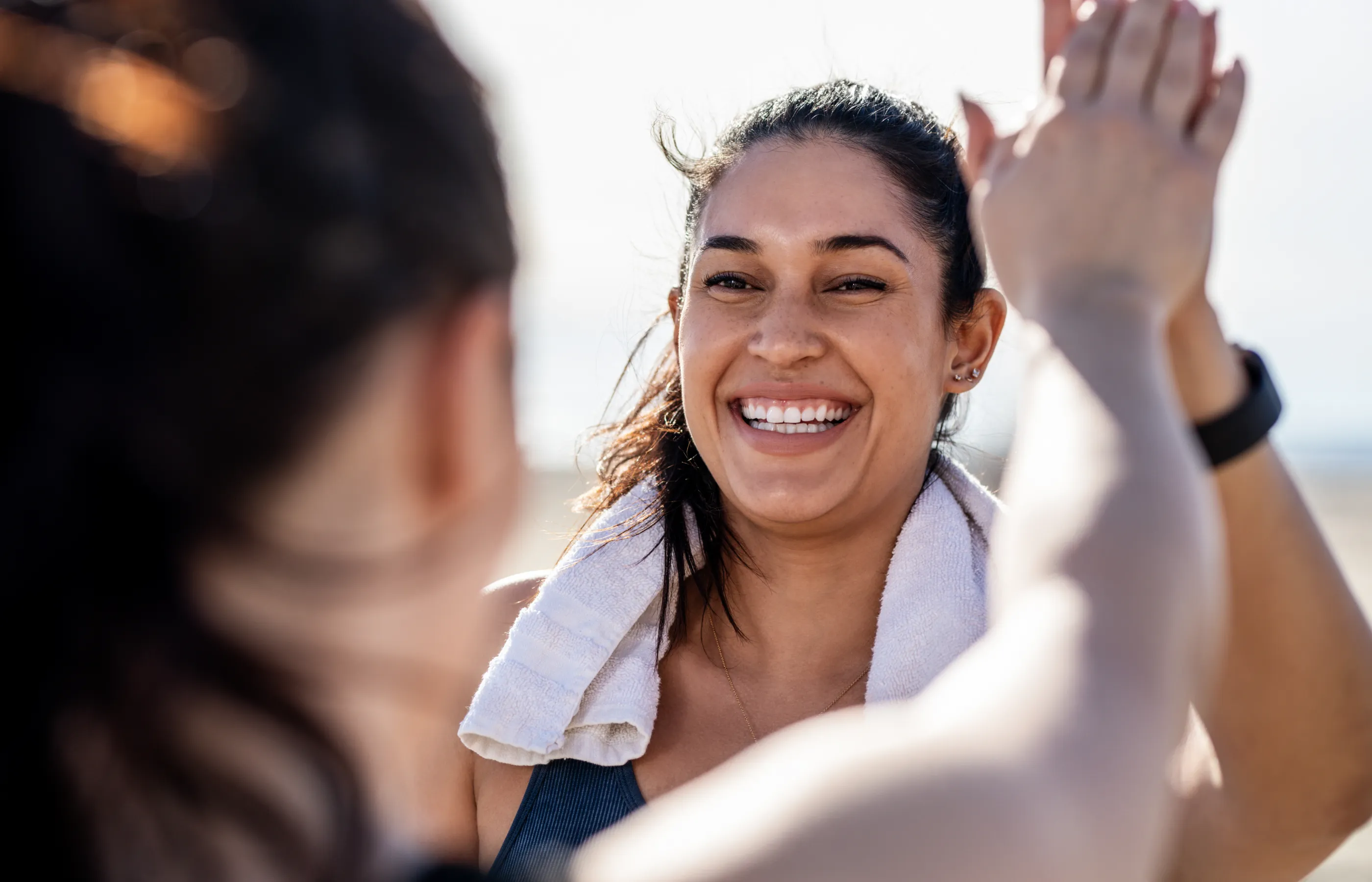 Two athletic women exercising outdoors giving each other a high five after completing their workout