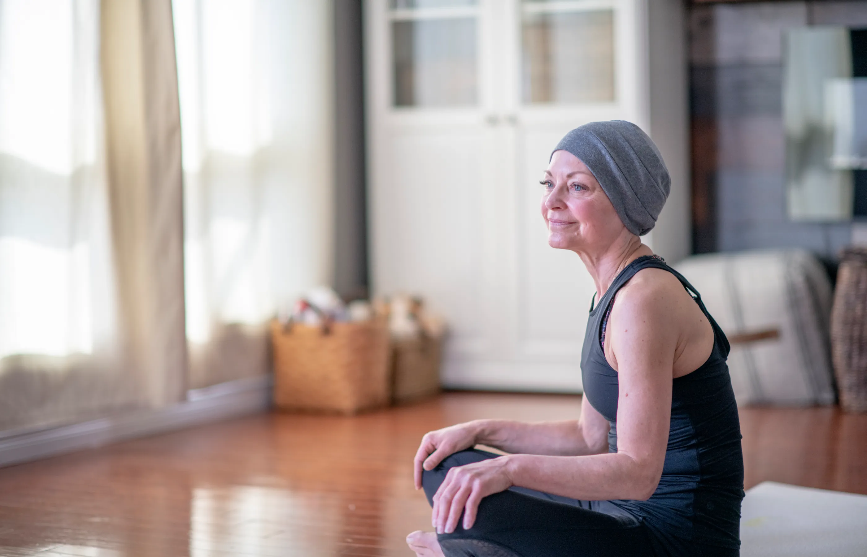 Cancer patient sitting on the floor in her home practicing yoga.