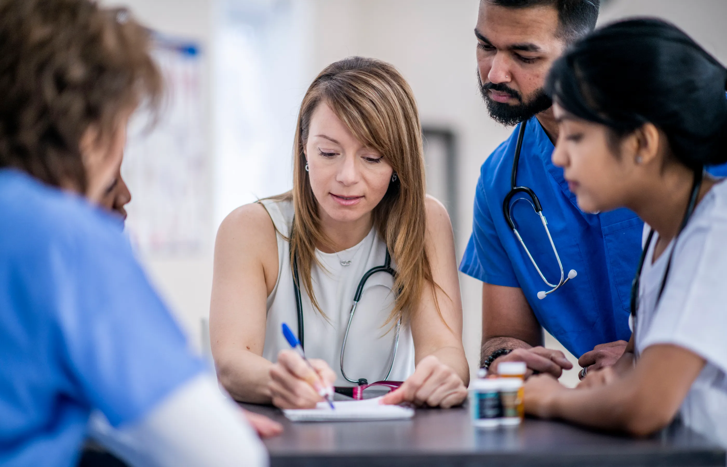 A group of residents are gathered around their preceptor as they listen and discuss. 