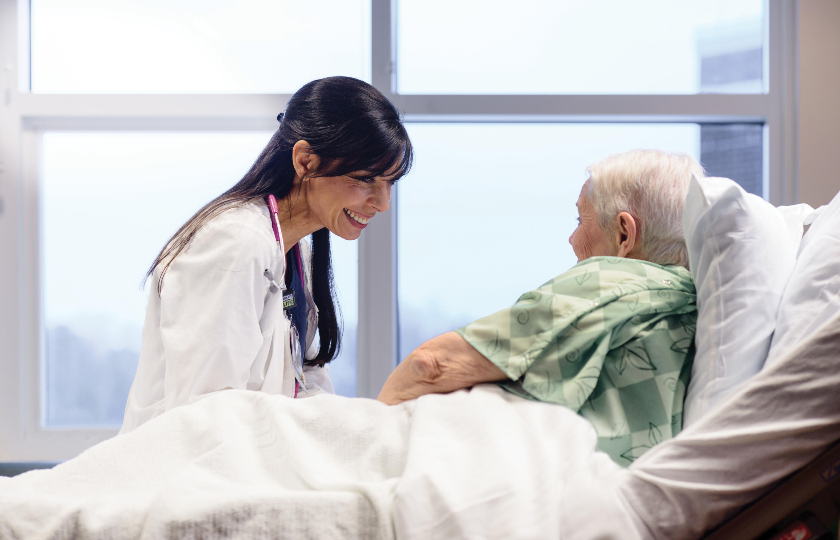 Smiling female nurse at the bedside of an elderly patient