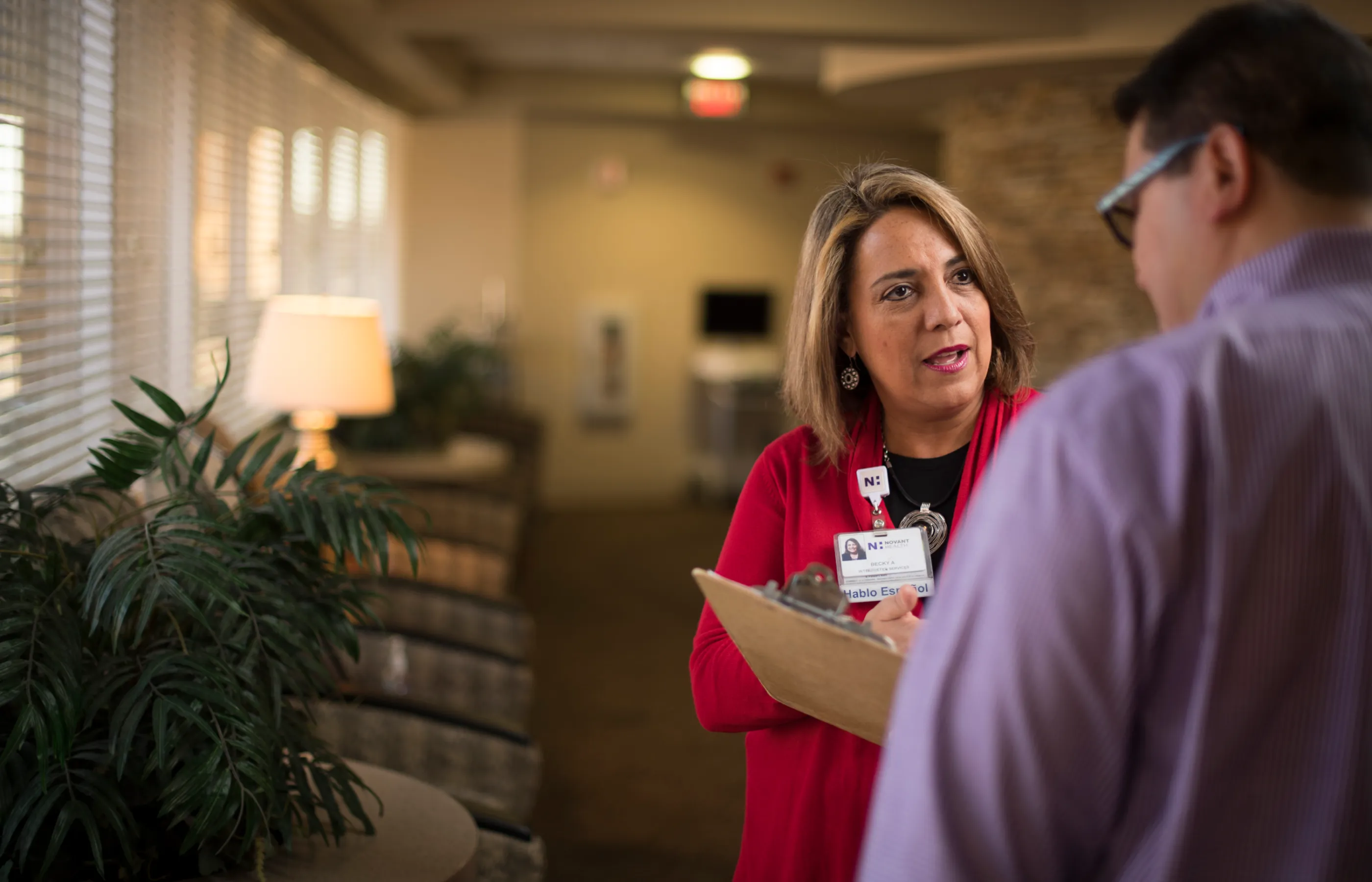 A Novant Health interpreter is talking with another person in a clinic lobby. 