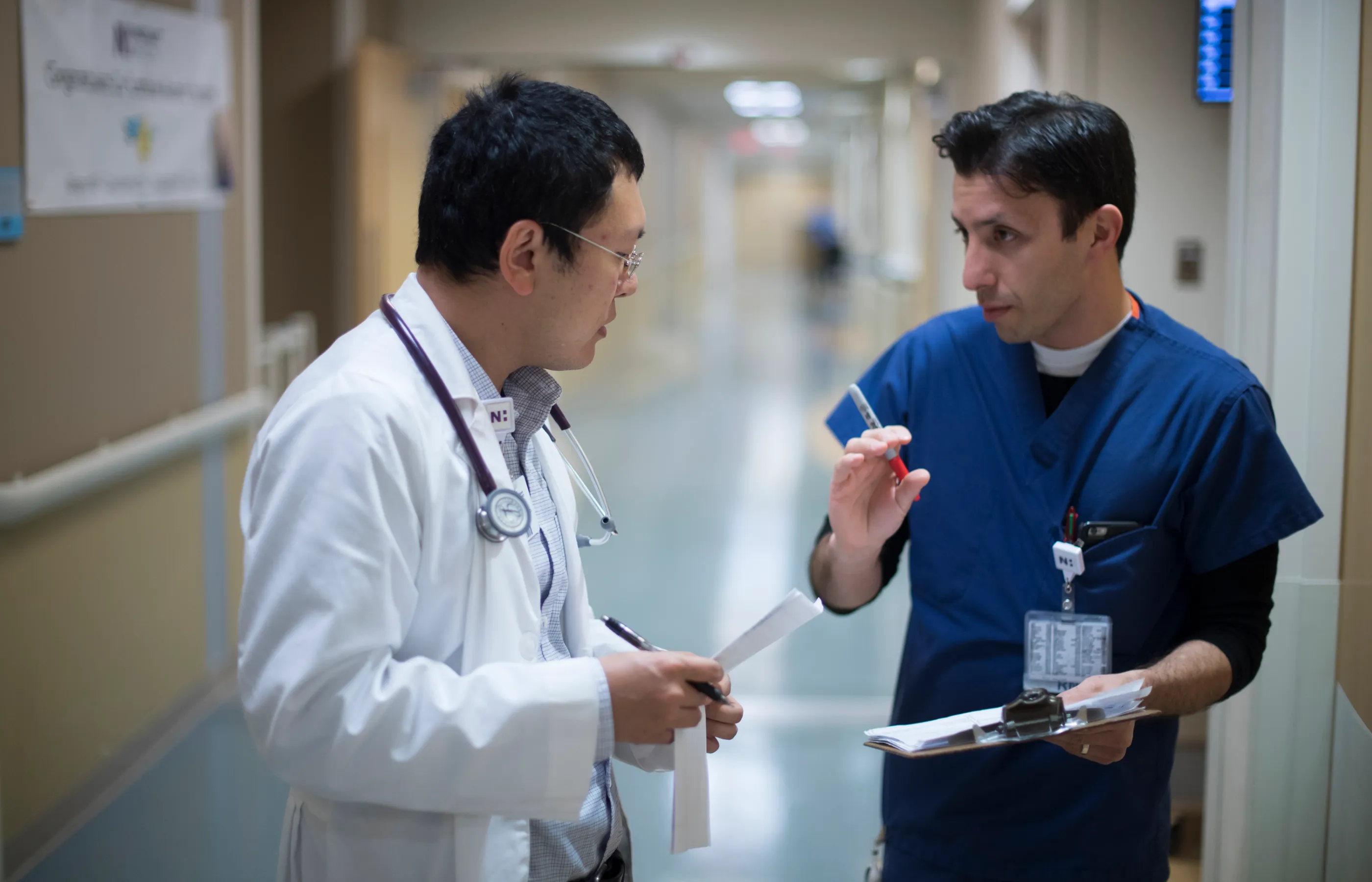 A Novant Health doctor and nurse are standing in the hall of a hospital as they discuss and plan together.