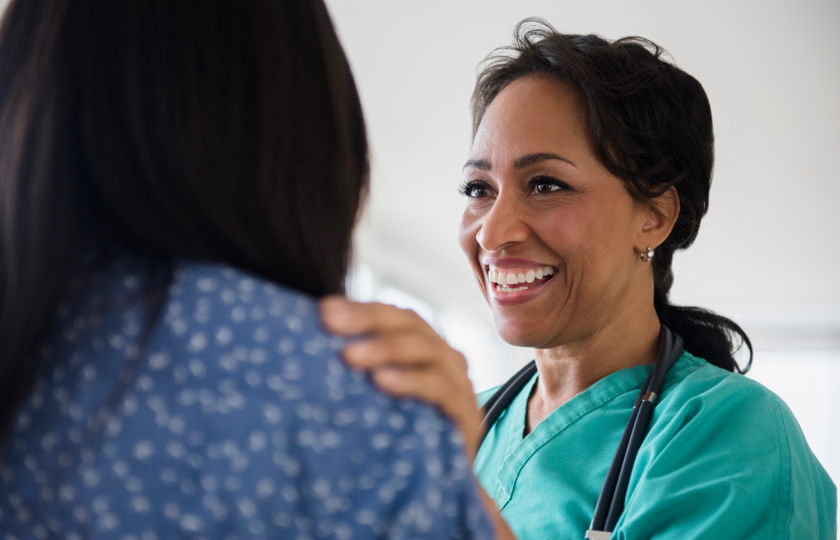 smiling nurse with her hand on the should of a female patient smiling nurse with her hand on the should of a female patient