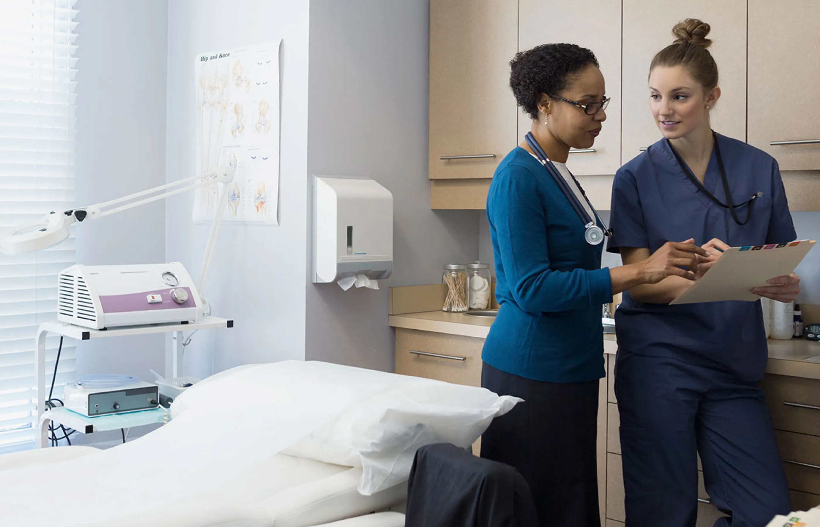 Two team members are reviewing information together in an exam room.