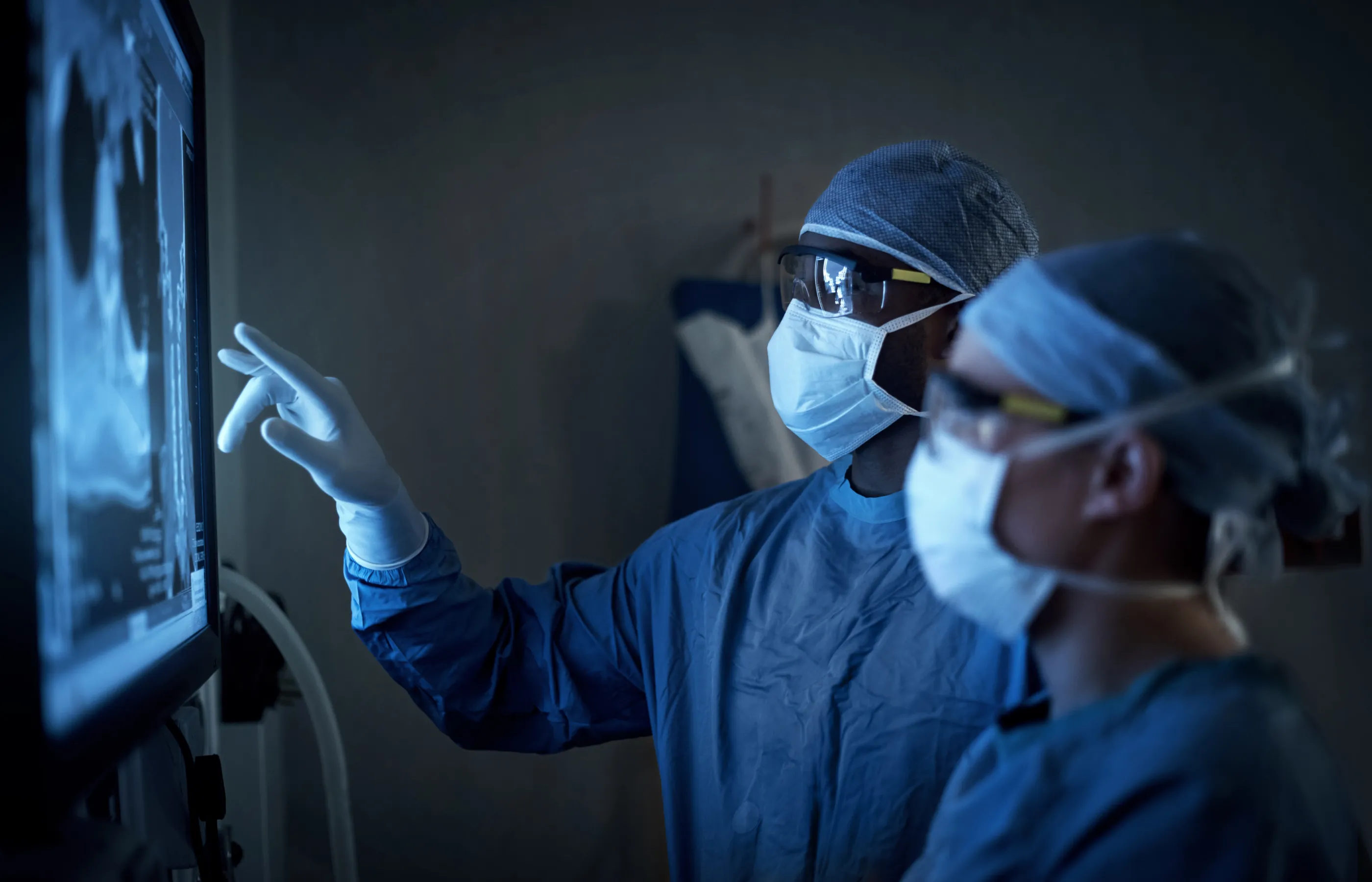 Two surgeons analyzing a patient’s medical scans during surgery Two surgeons analyzing a patient’s medical scans during surgery