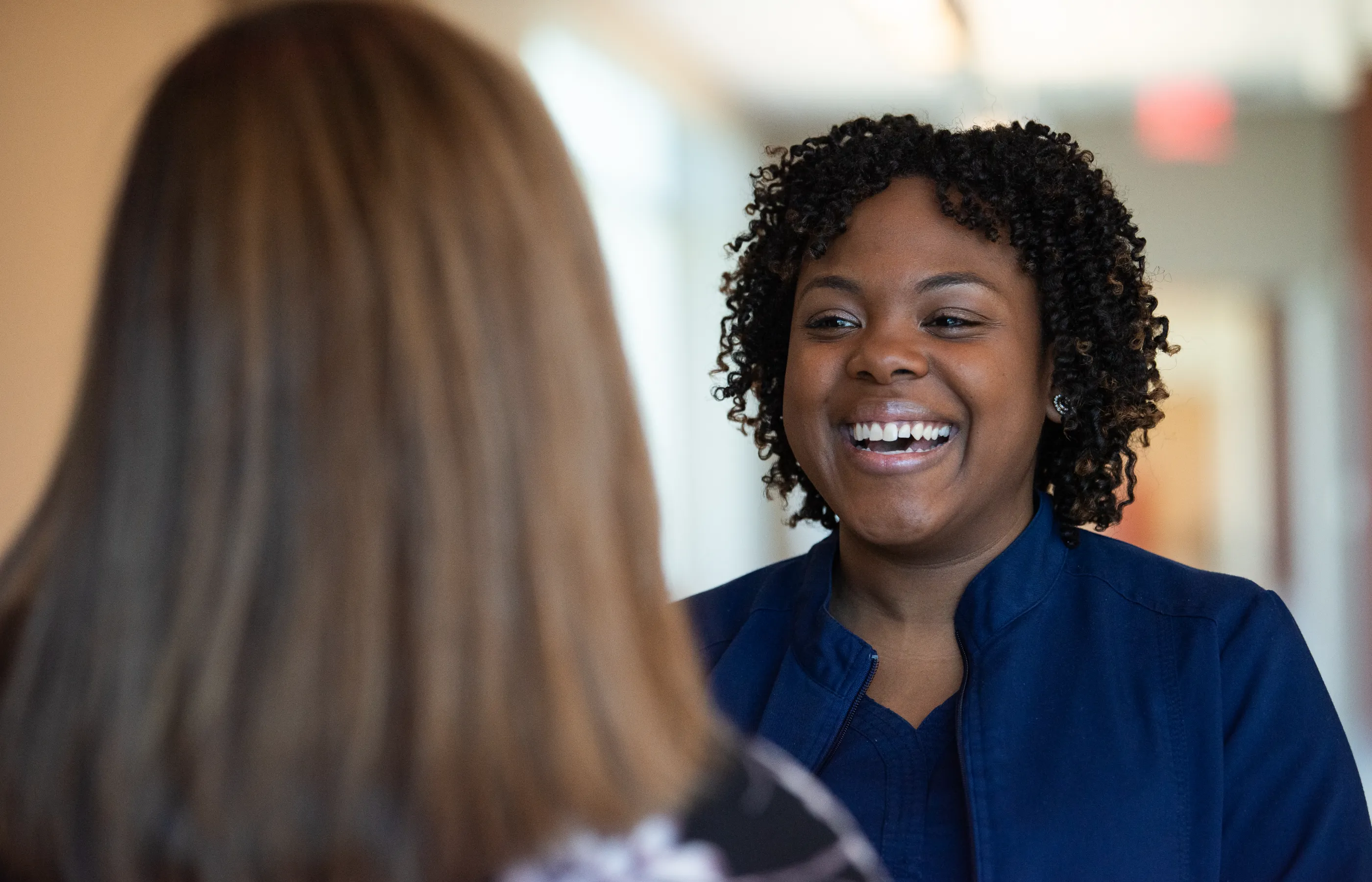 Two registered nurses are talking and laughing with each other. 