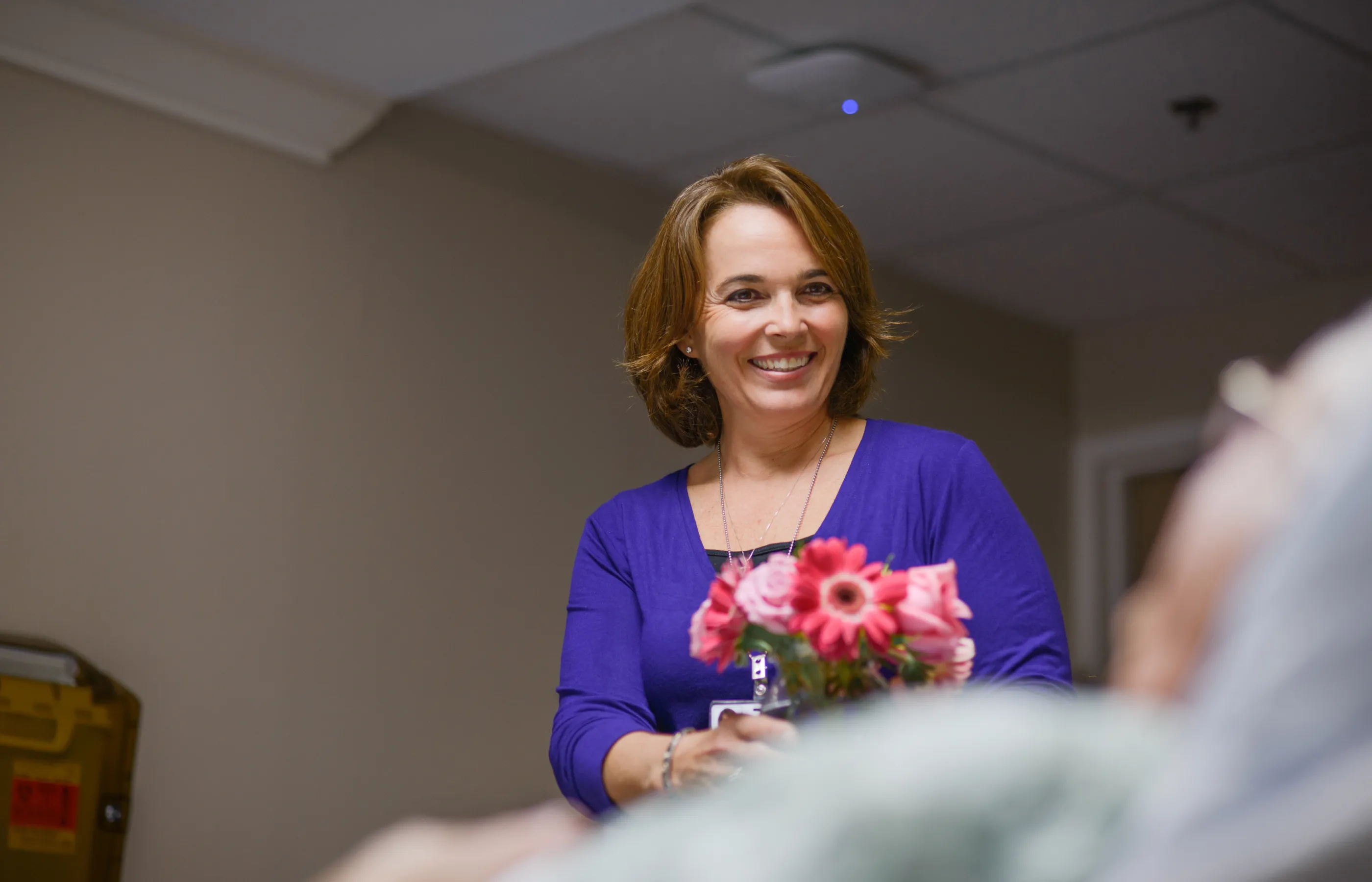 A team member is delivering flowers to a patient. A team member is delivering flowers to a patient.