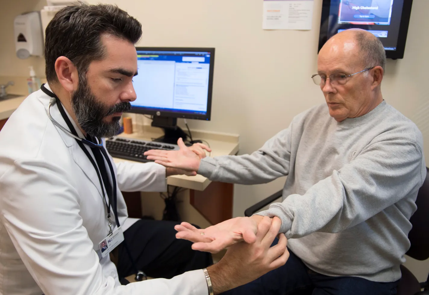 Dr. Delgado is sitting across from a patient in an exam room. The patient is holding their palms face up as Dr. Delgado examines them. Dr. Delgado is sitting across from a patient in an exam room. The patient is holding their palms face up as Dr. Delgado examines them.