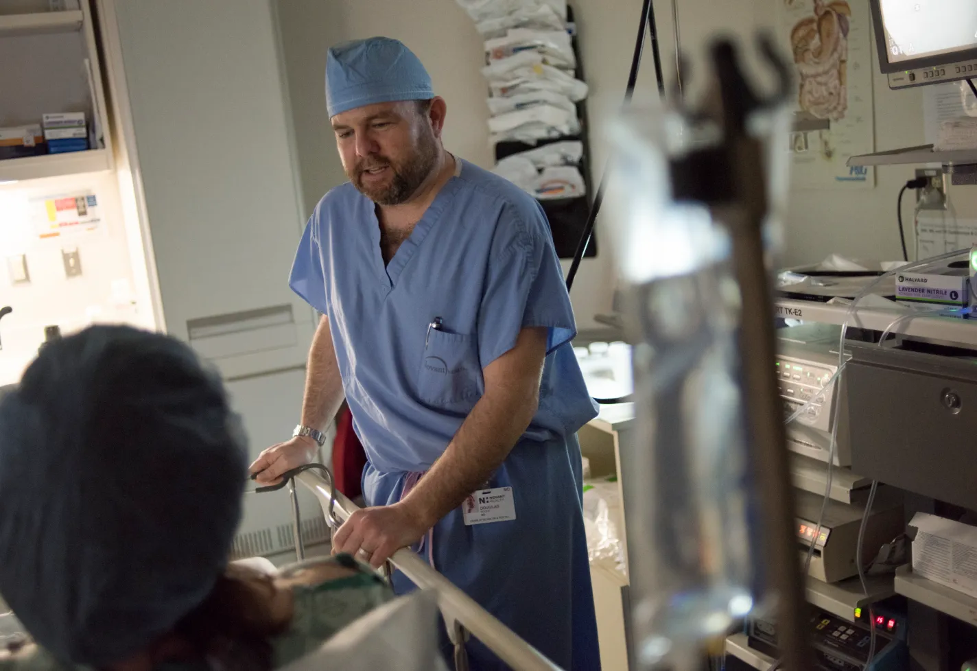 Novant Health's Dr. Douglas is standing at a patient's bedside, talking as they prepare for surgery. 