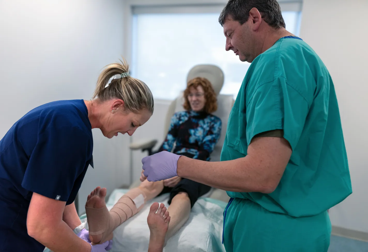 Dr. Versnick and a nurse are wrapping the leg and foot wound of a patient. Dr. Versnick and a nurse are wrapping the leg and foot wound of a patient.