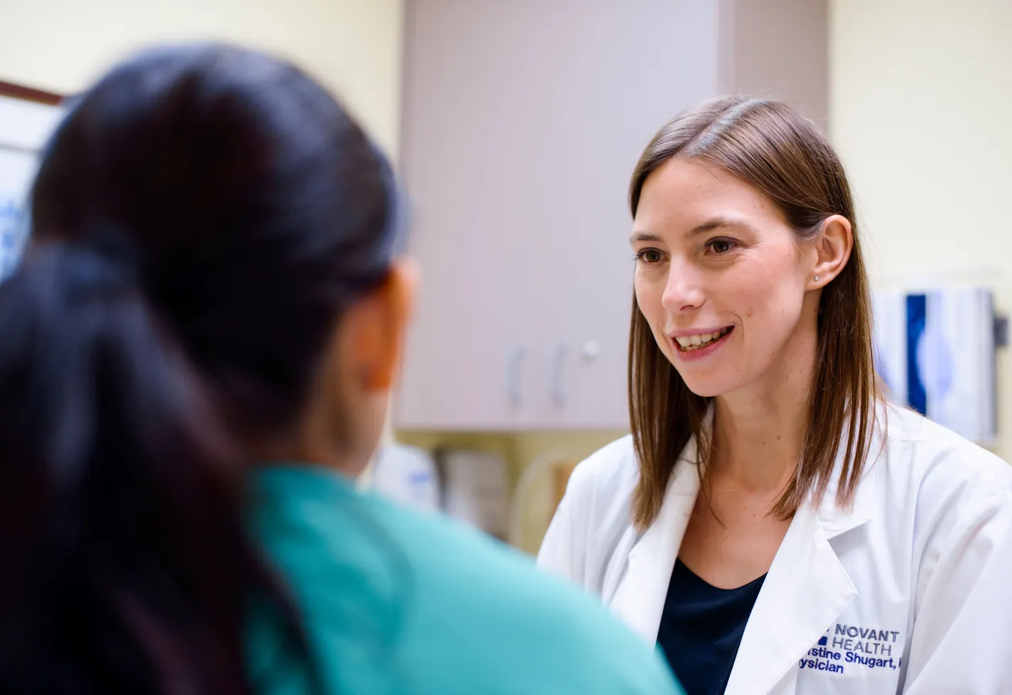 Dr. Shugart, a Novant Health physician, is talking with a patient as they sit in the exam room.