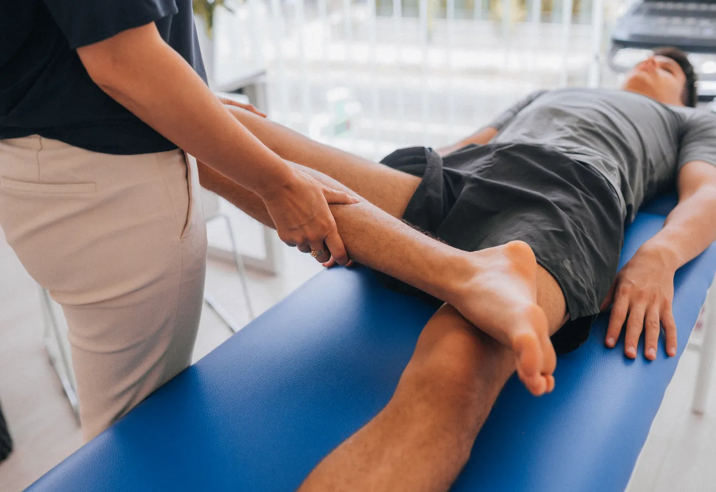 A physical therapist is guiding a patient's knee as they stretch. 