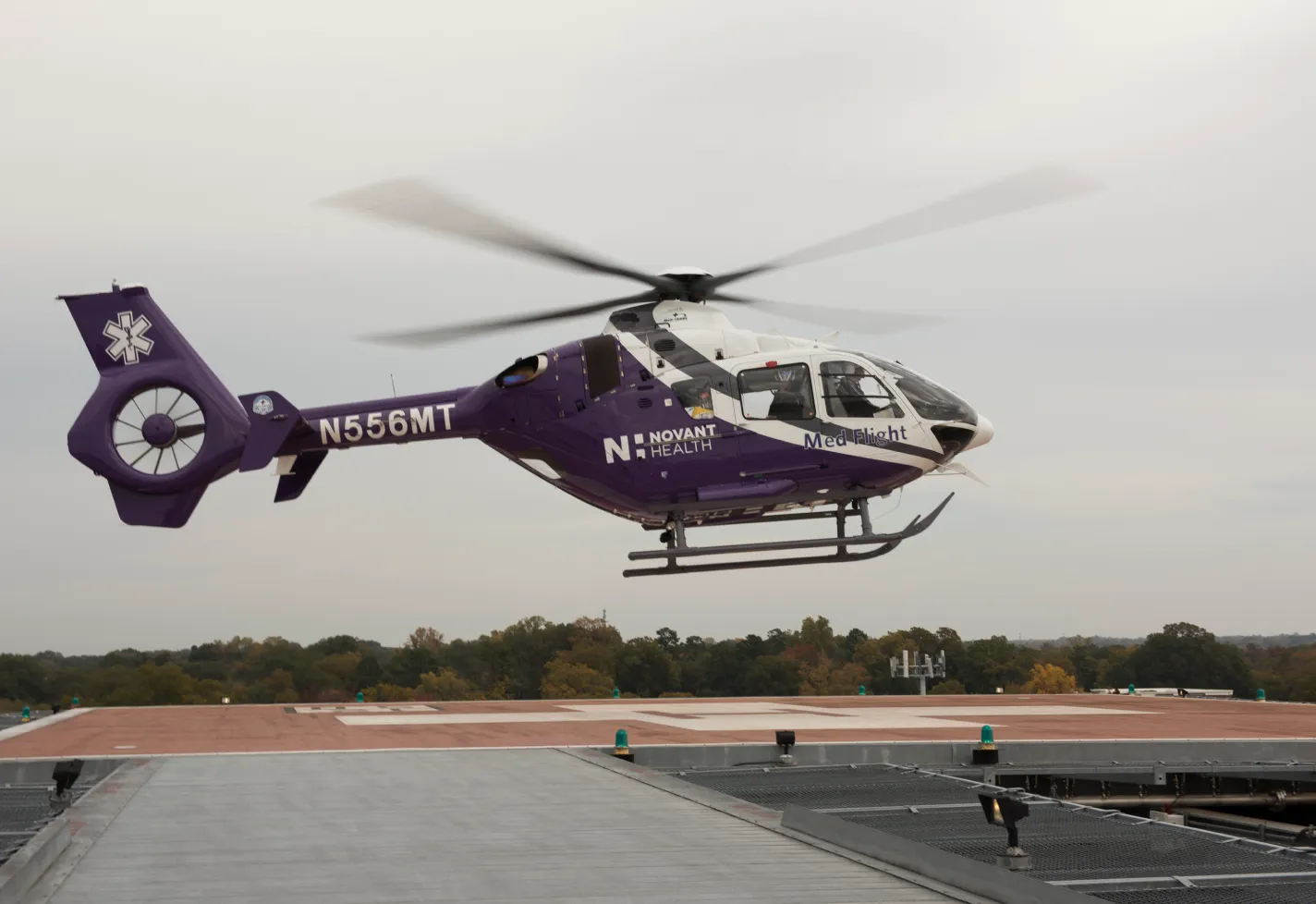 A Novant Health helicopter is hovering over a launch pad. A Novant Health helicopter is hovering over a launch pad.