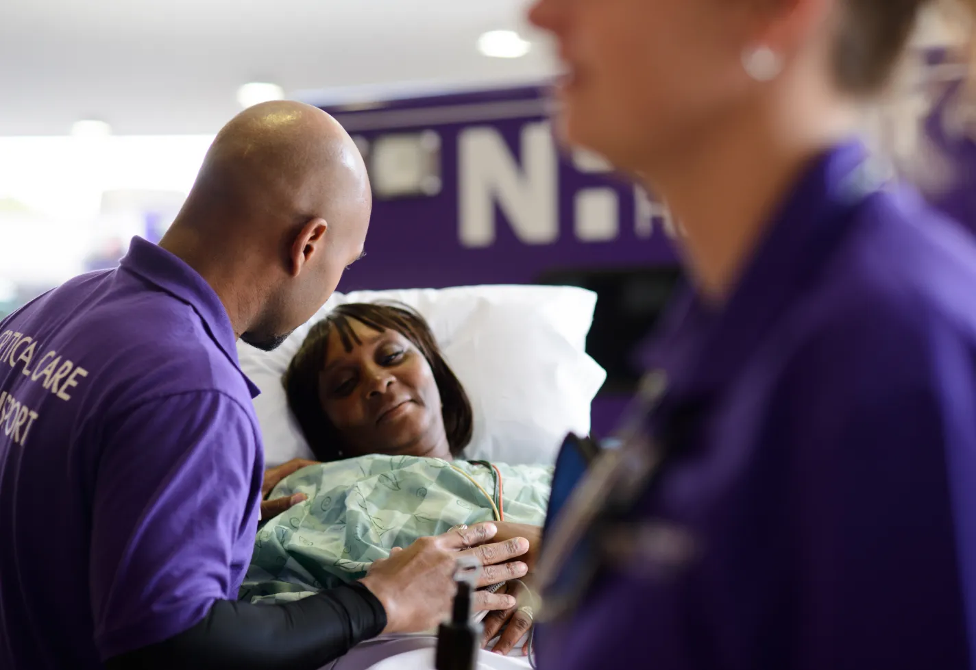 Novant Health critical care transport team members assisting and supporting a woman on stretcher. Novant Health critical care transport team members assisting and supporting a woman on stretcher.