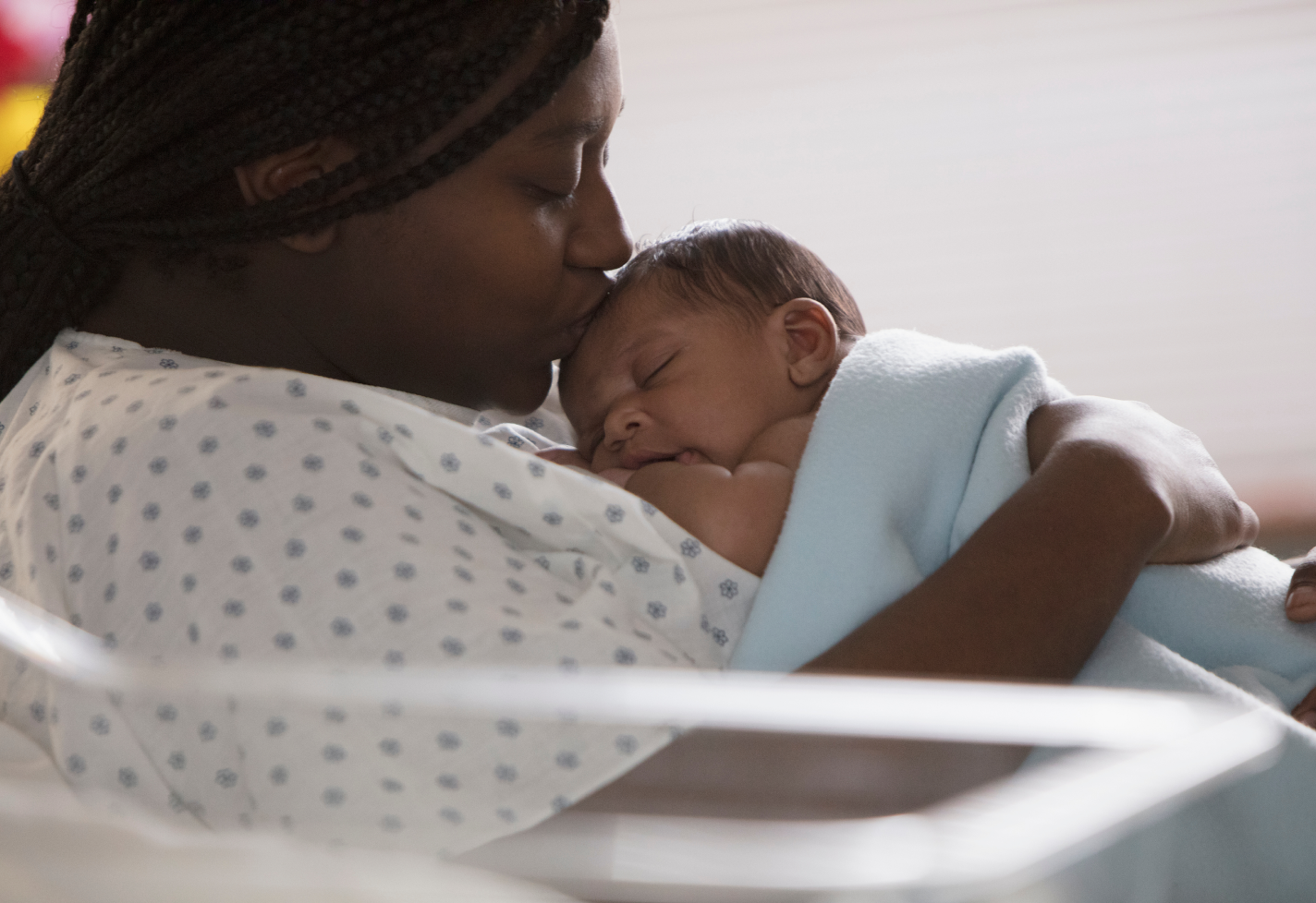 A mother is kissing her newborn babies head as they lay on her chest. A mother is kissing her newborn babies head as they lay on her chest.