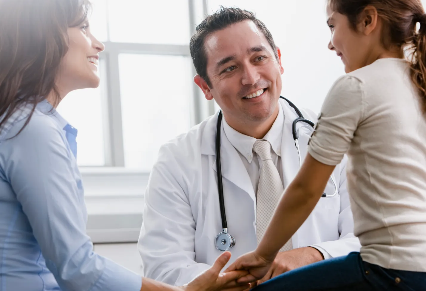 A mother and daughter are sitting in a doctors visit with a healthcare provider. A mother and daughter are sitting in a doctors visit with a healthcare provider.