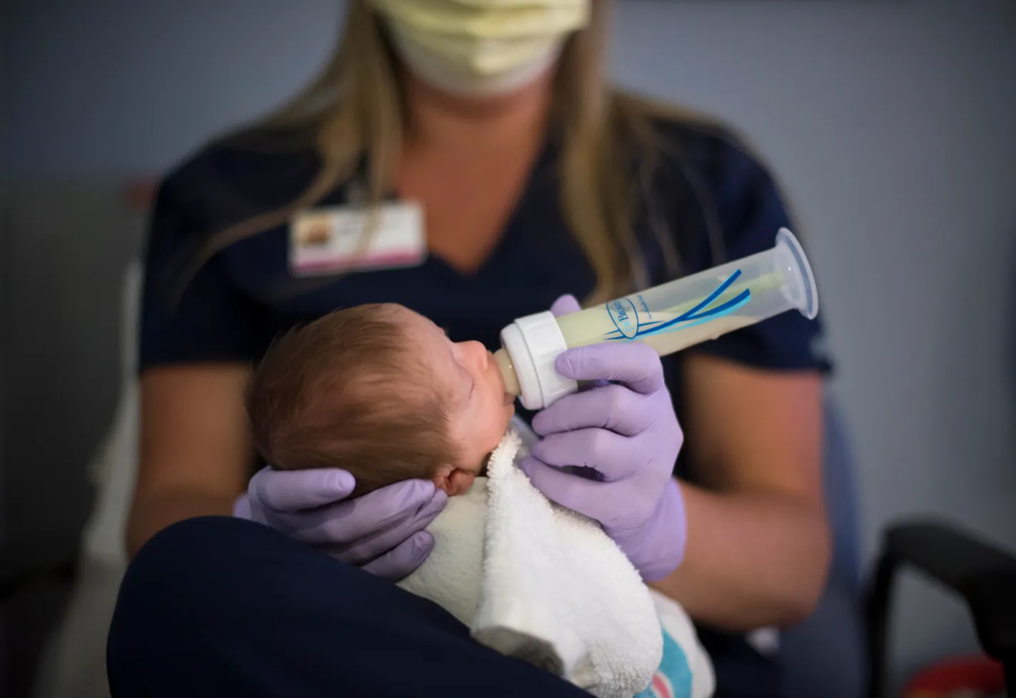 A Novant Health nurse is wearing gloves as she holds a newborn baby and feeds them a bottle. A Novant Health nurse is wearing gloves as she holds a newborn baby and feeds them a bottle.