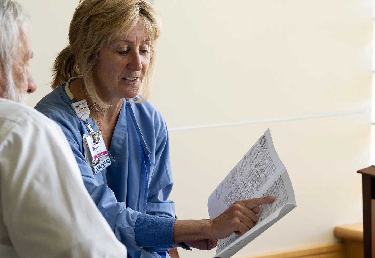 A Novant Health nurse is holding paperwork as she explains information to a patient. 