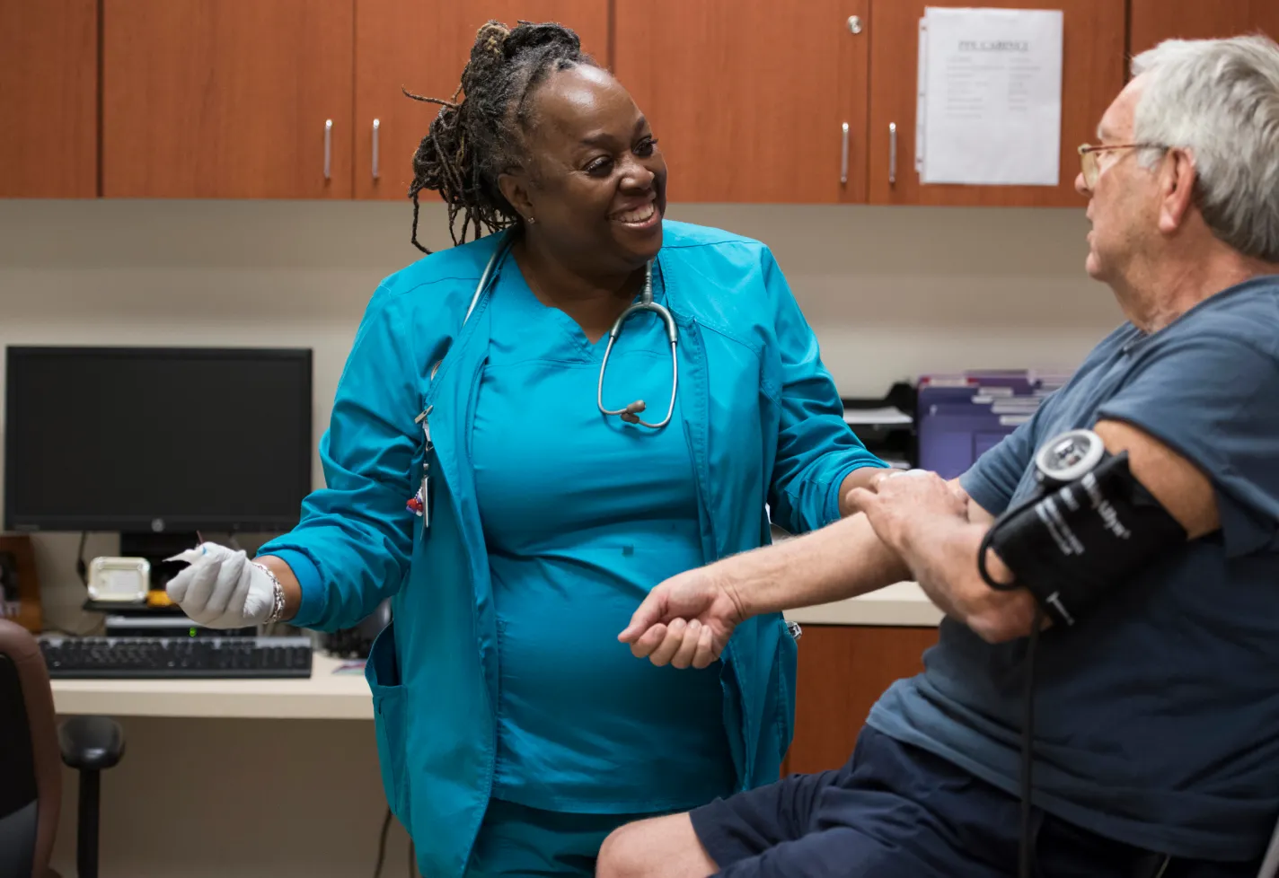 A Novant Health lab specialist and patient are in clinic lab taking blood pressure and completing lab testing.