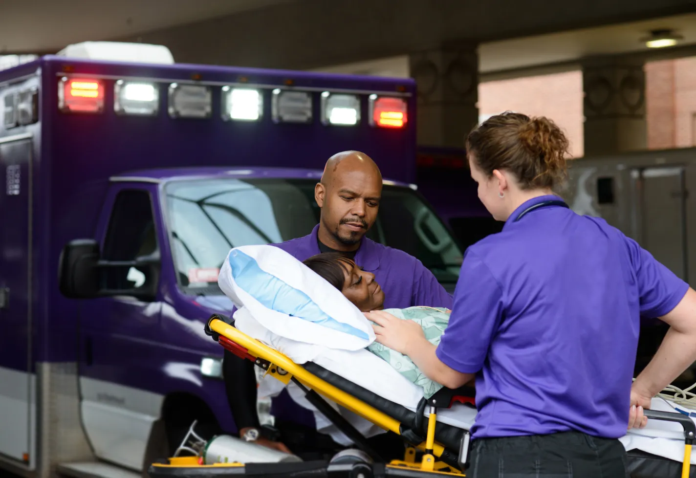 Two Novant Health team members are wheeling a patient on a stretcher. Two Novant Health team members are wheeling a patient on a stretcher.