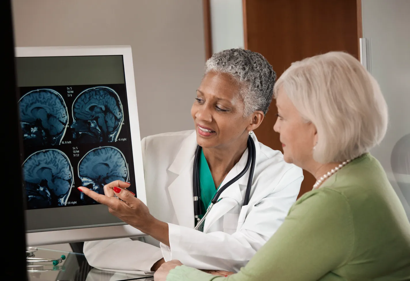 Physician and a senior woman view a brain imaging screen Physician and a senior woman view a brain imaging screen