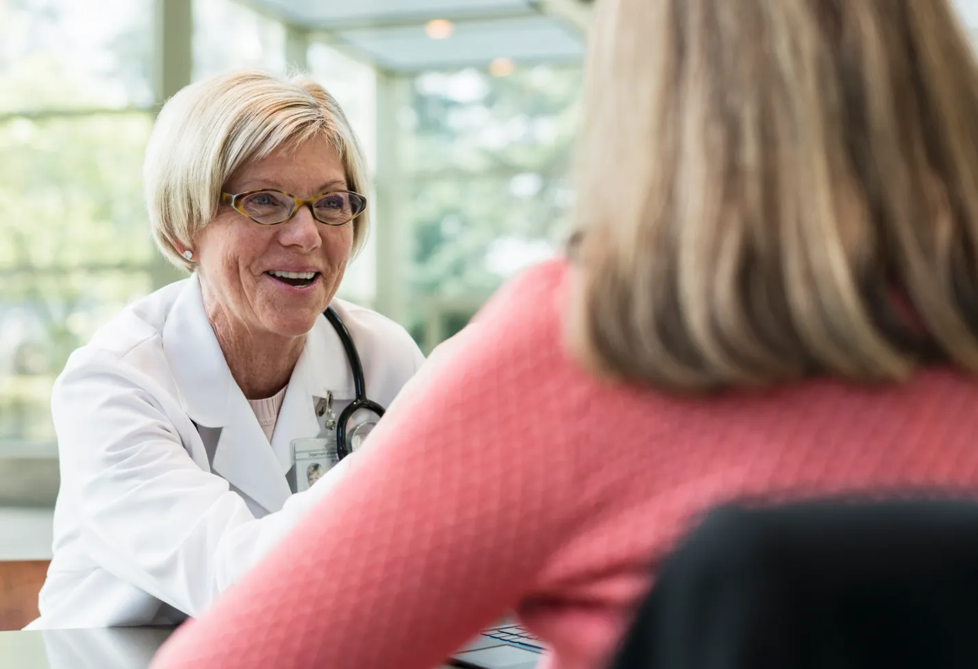 A health care provider is sitting across from her patient sharing information with her. 