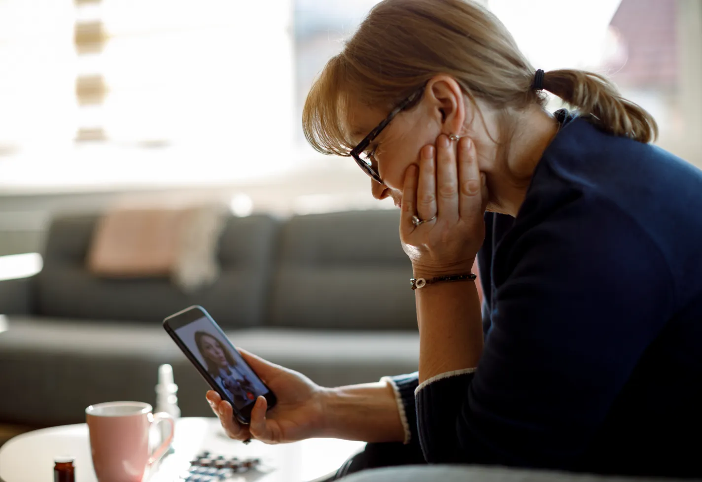 A woman is using her smart phone to have a virtual visit with her health care provider.