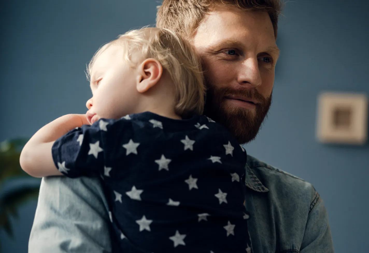 A father is smiling as he hugs his young child. 