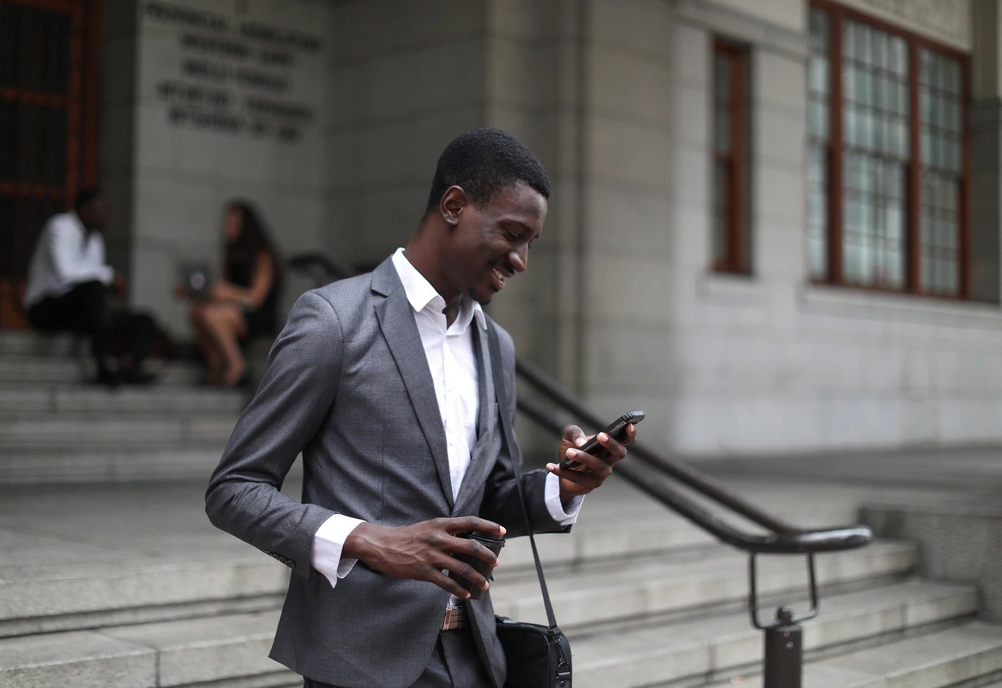 A man wearing a suit going down stairs while looking at a smart phone. A man wearing a suit going down stairs while looking at a smart phone.