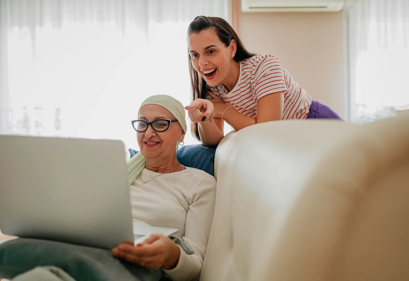 A cancer patient and her daughter are reviewing information on a laptop computer. 