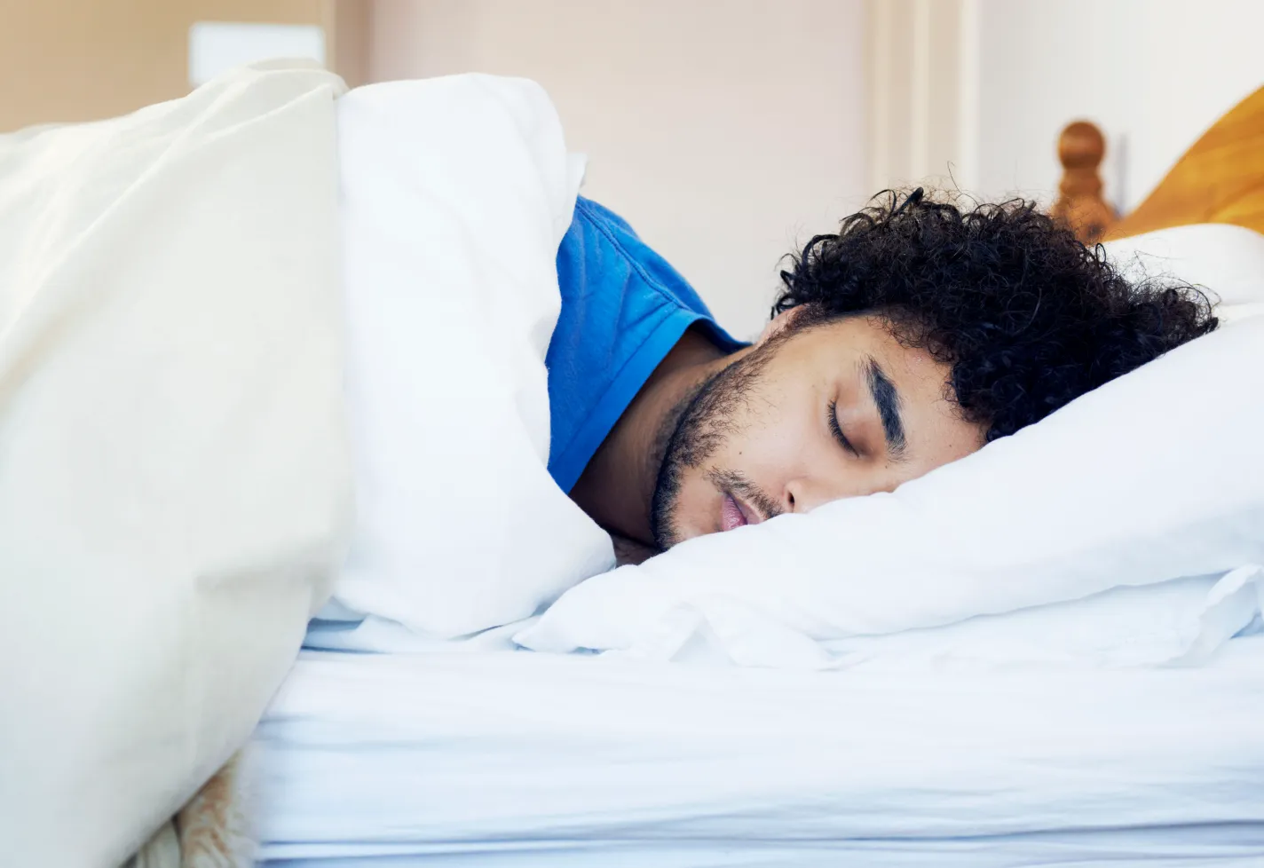 A man with curly hair sleeps in his bed. A man with curly hair sleeps in his bed.